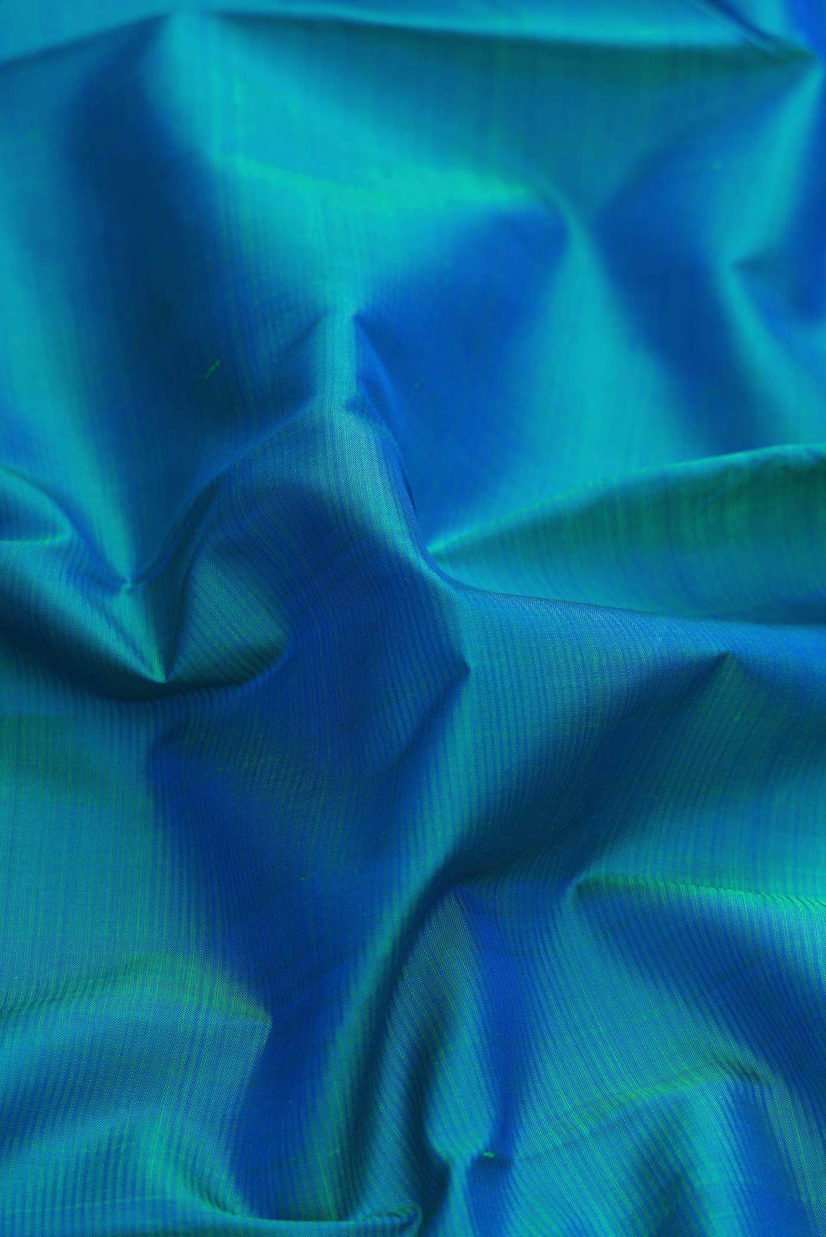 Close up of Peacock Blue Dual Tone Kanchipuram Silk Saree with Plain Body and Zari Border displaying folds