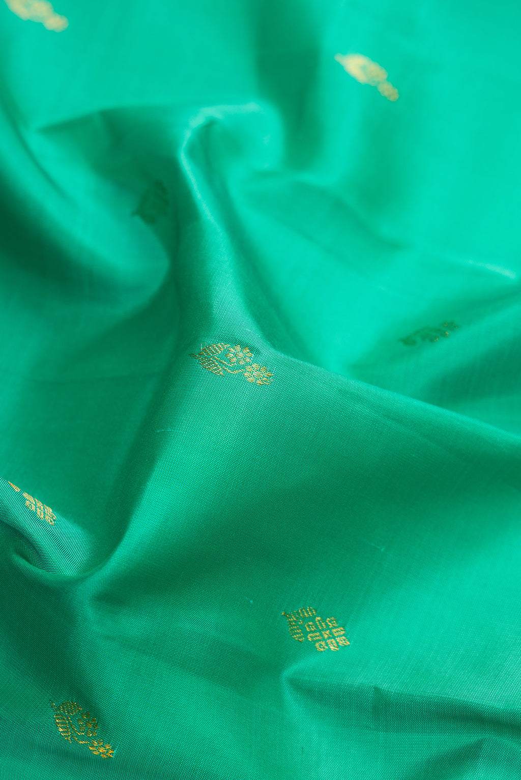 Close up of Green Dual Tone Kanchipuram Silk Saree with Zari Butta on the body and Zari Border.  displaying folds