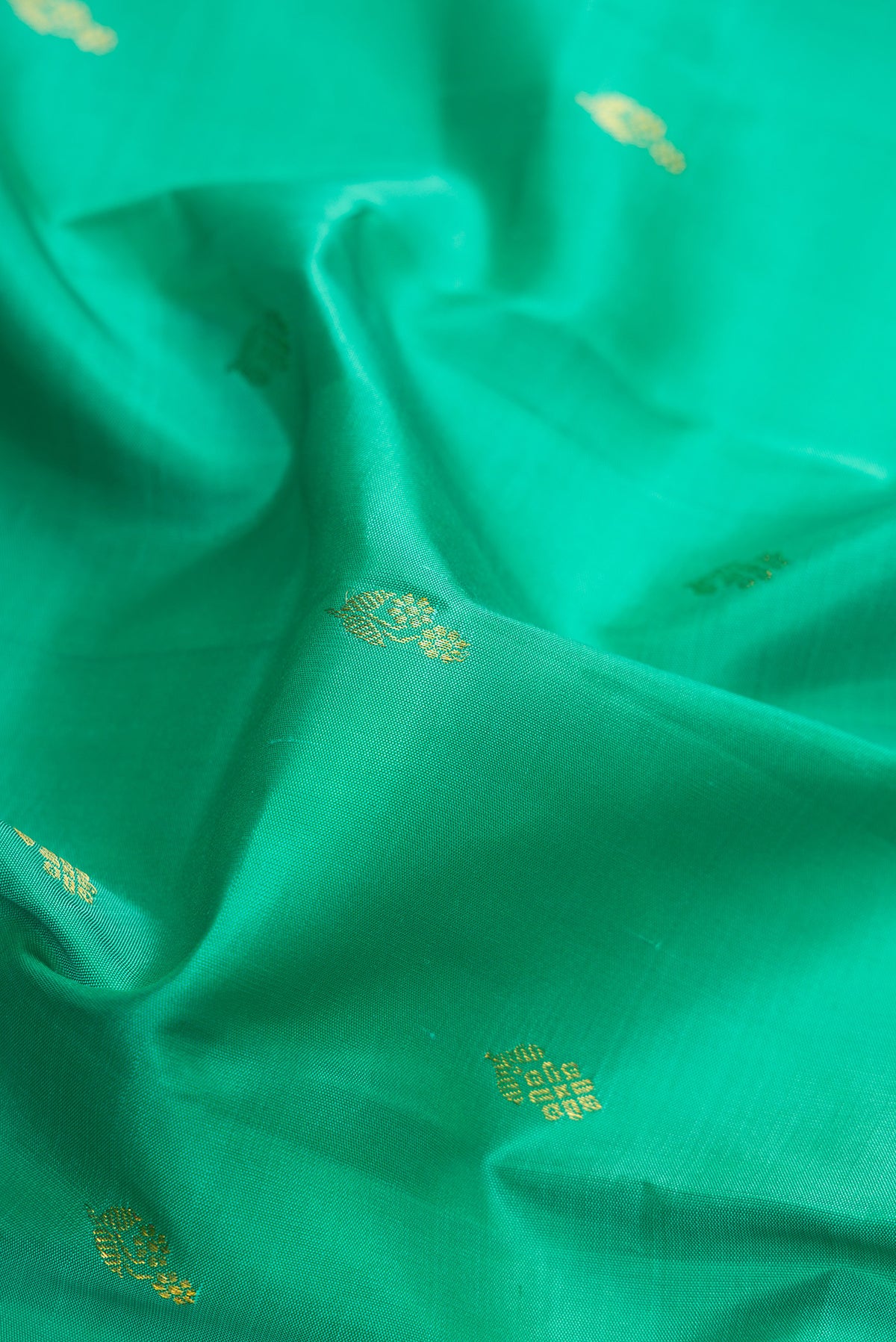 Close up of Green Dual Tone Kanchipuram Silk Saree with Zari Butta on the body and Zari Border.  displaying folds