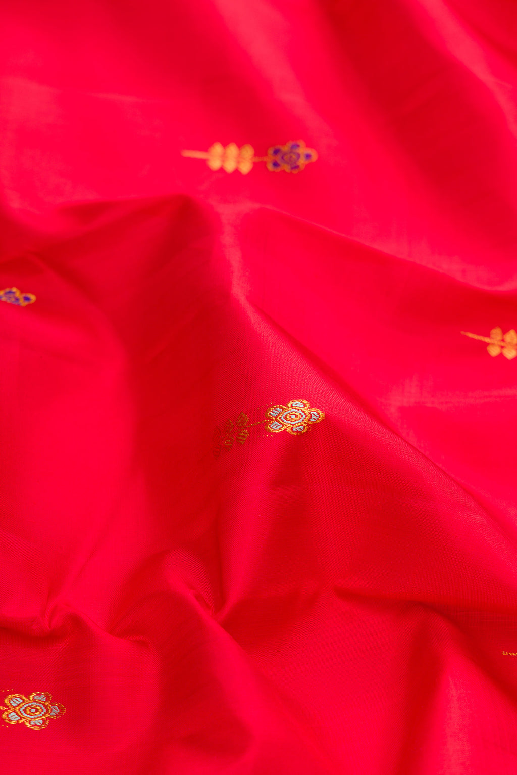 Close up of Red Dual Tone Kanchipuram Silk Saree with Zari And Thread Butta on the body and Zari Border.  displaying folds