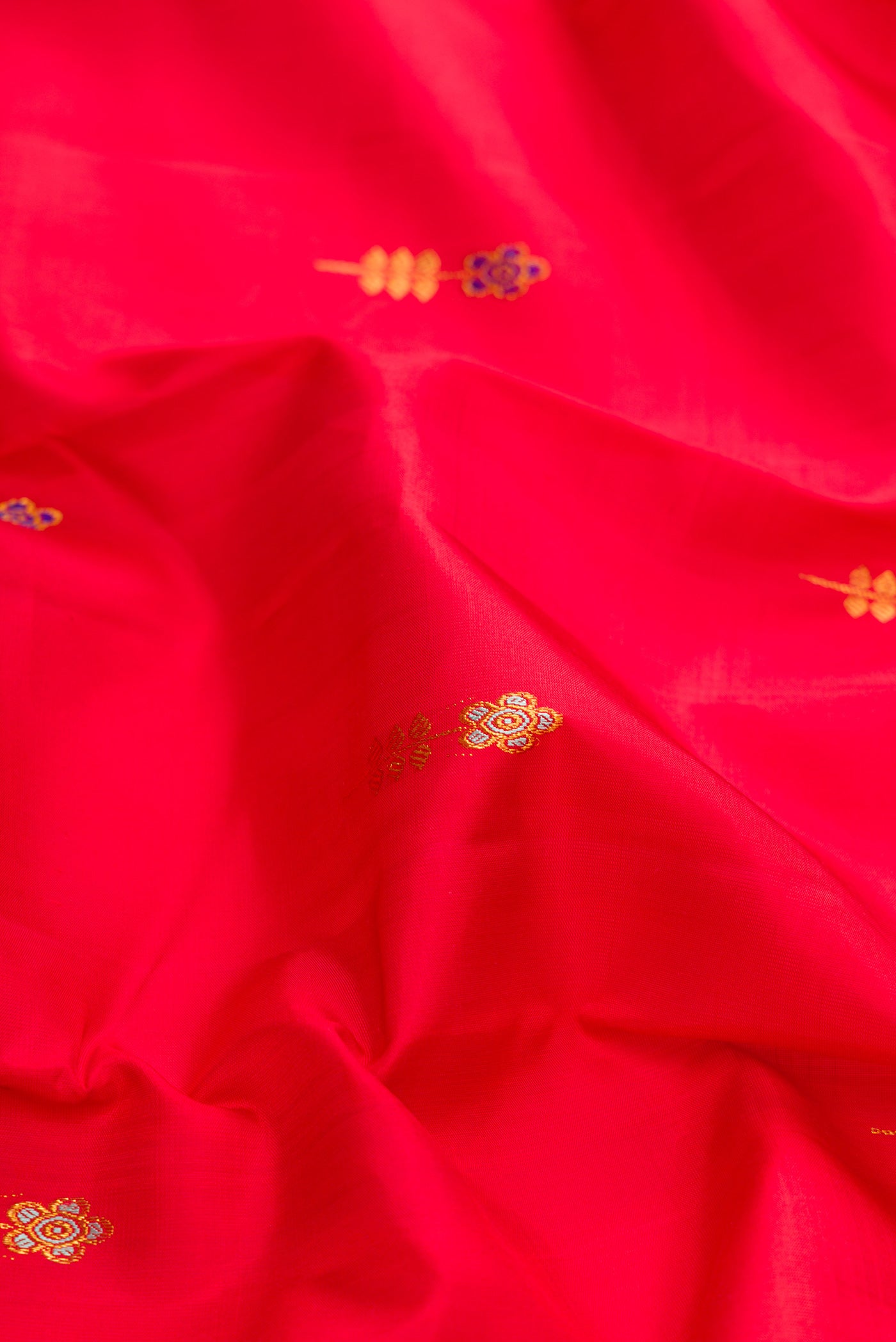 Close up of Red Dual Tone Kanchipuram Silk Saree with Zari And Thread Butta on the body and Zari Border.  displaying folds