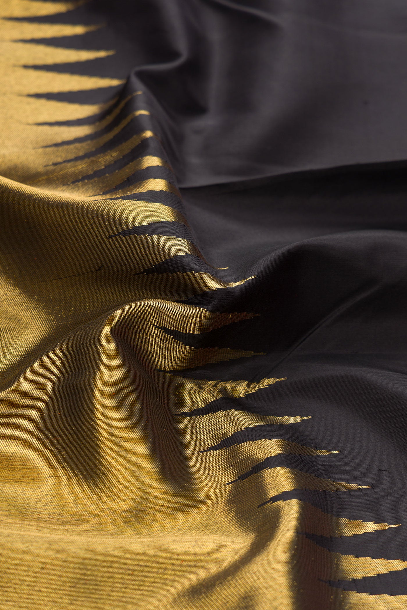 Close up of Black Dual Tone Kanchipuram Silk Saree with Plain Body and Rising Temple Border.  displaying folds