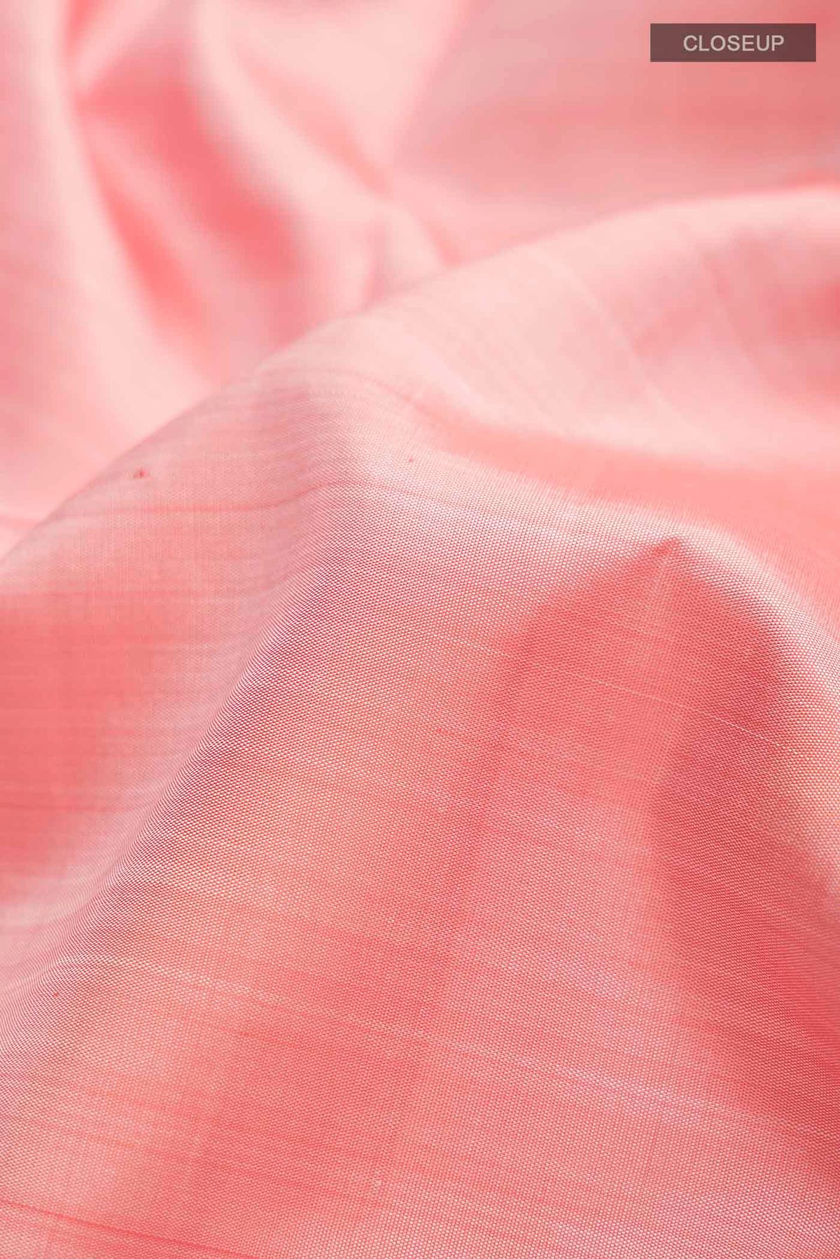 Close up of Peach Kanchipuram Silk Saree with Plain Body and Zari Border displaying folds