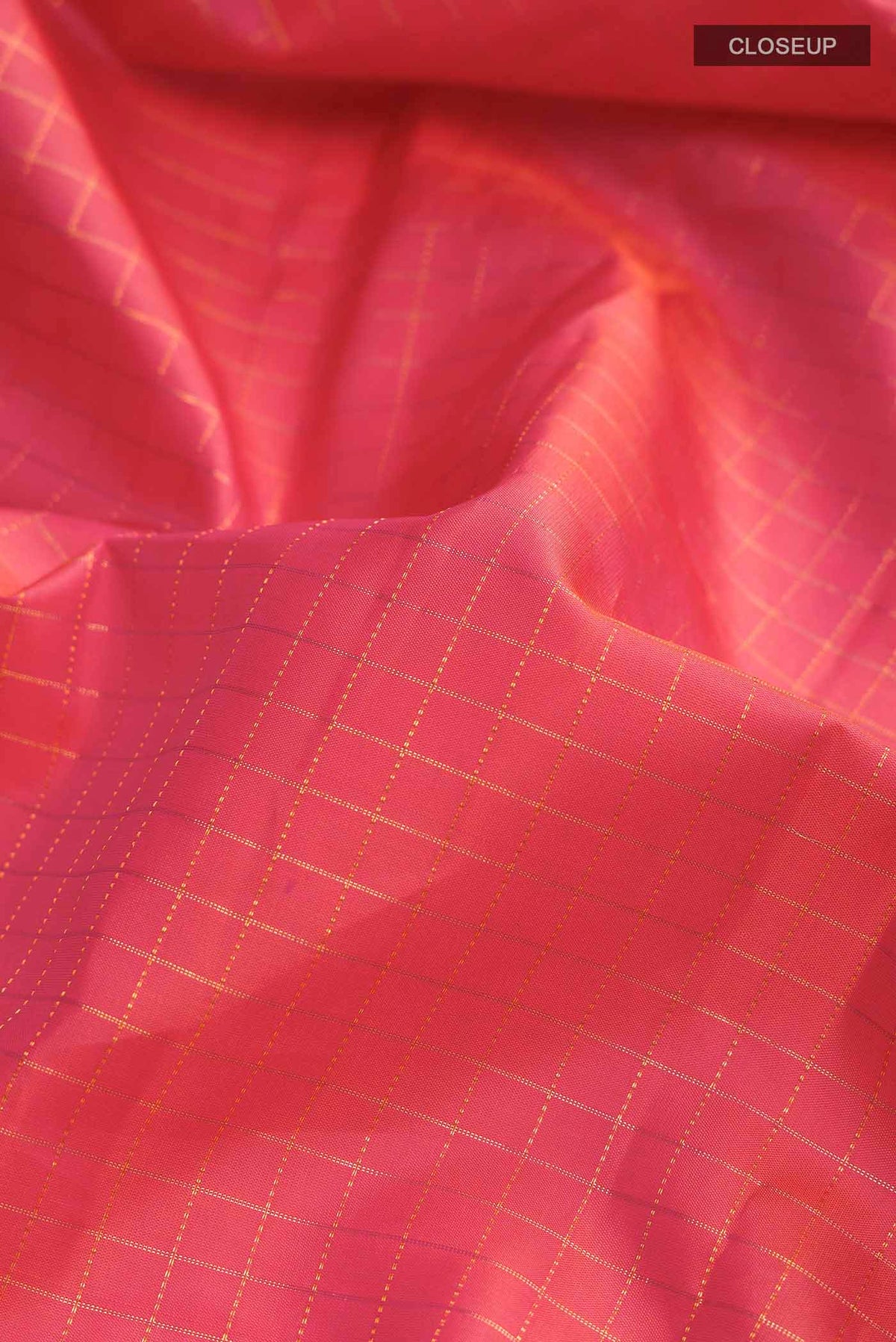 Close up of Orange with Pink Color Kanchipuram Silk Saree with Checked design on the body and Zari Border displaying folds