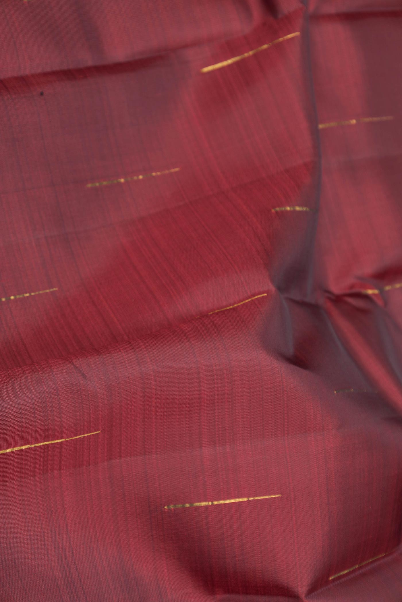 Close up of Maroon Dual Tone Kanchipuram Saree with Zari Butta on the body and Zari Border displaying folds