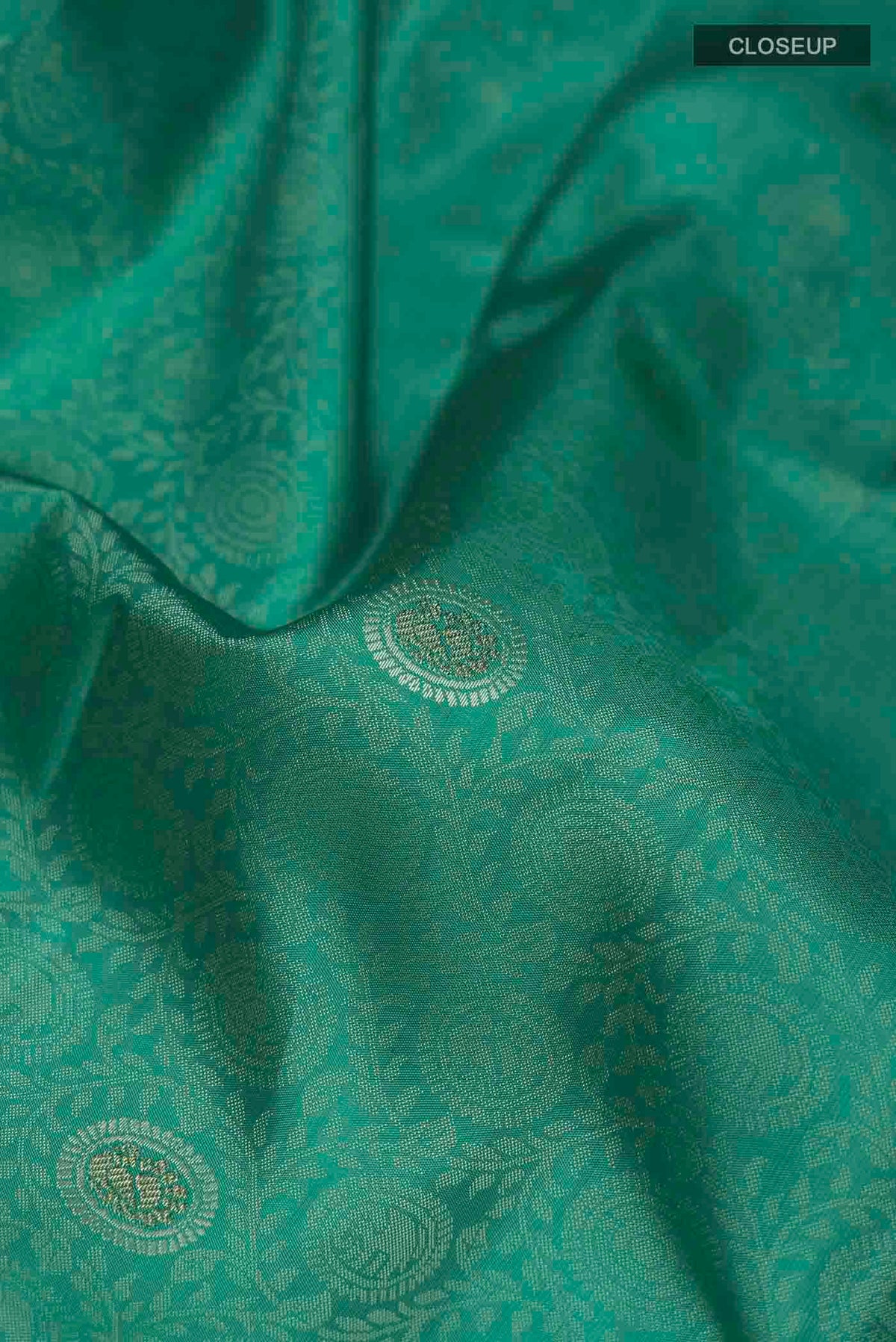 Close up of Turquoise Kanchipuram Silk Saree with Zari And Thread Butta on the body and Zari Border displaying folds