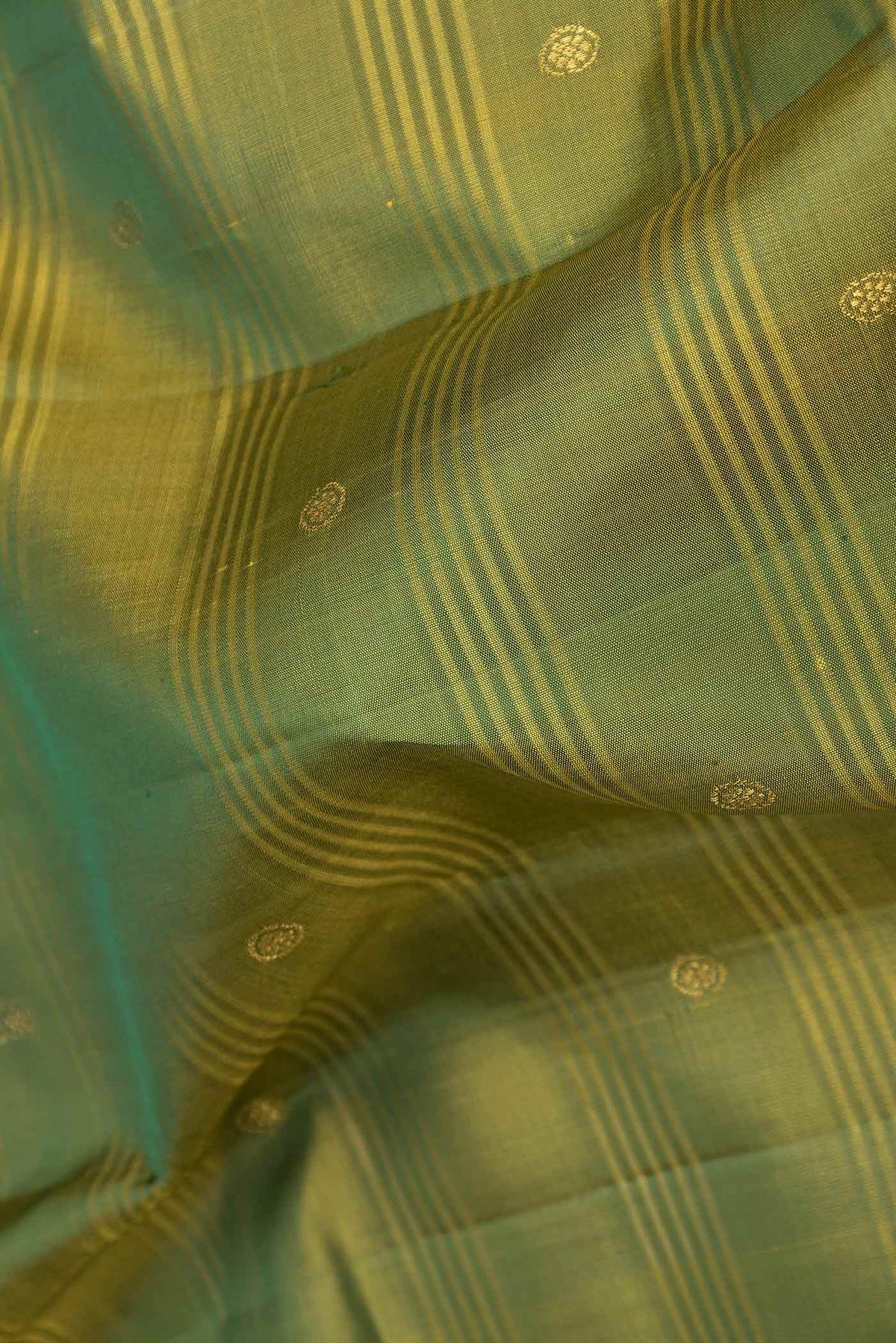 Close up of Mehandi Green Dual Tone Kanchipuram Saree with Zari Butta on the body and Zari Border displaying folds