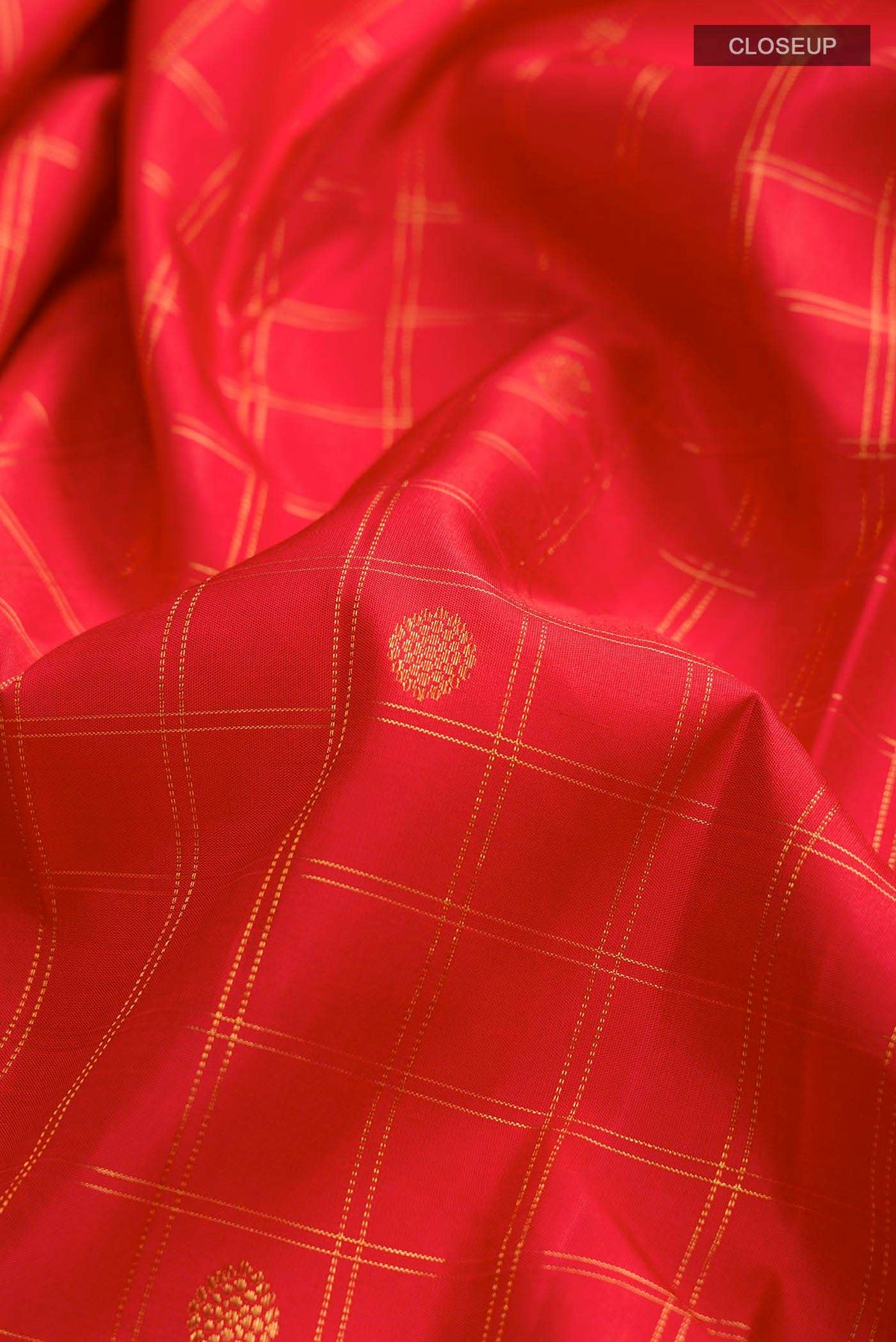 Close up of Red Kanchipuram Silk Saree with Zari Butta on the body and Zari Border displaying folds