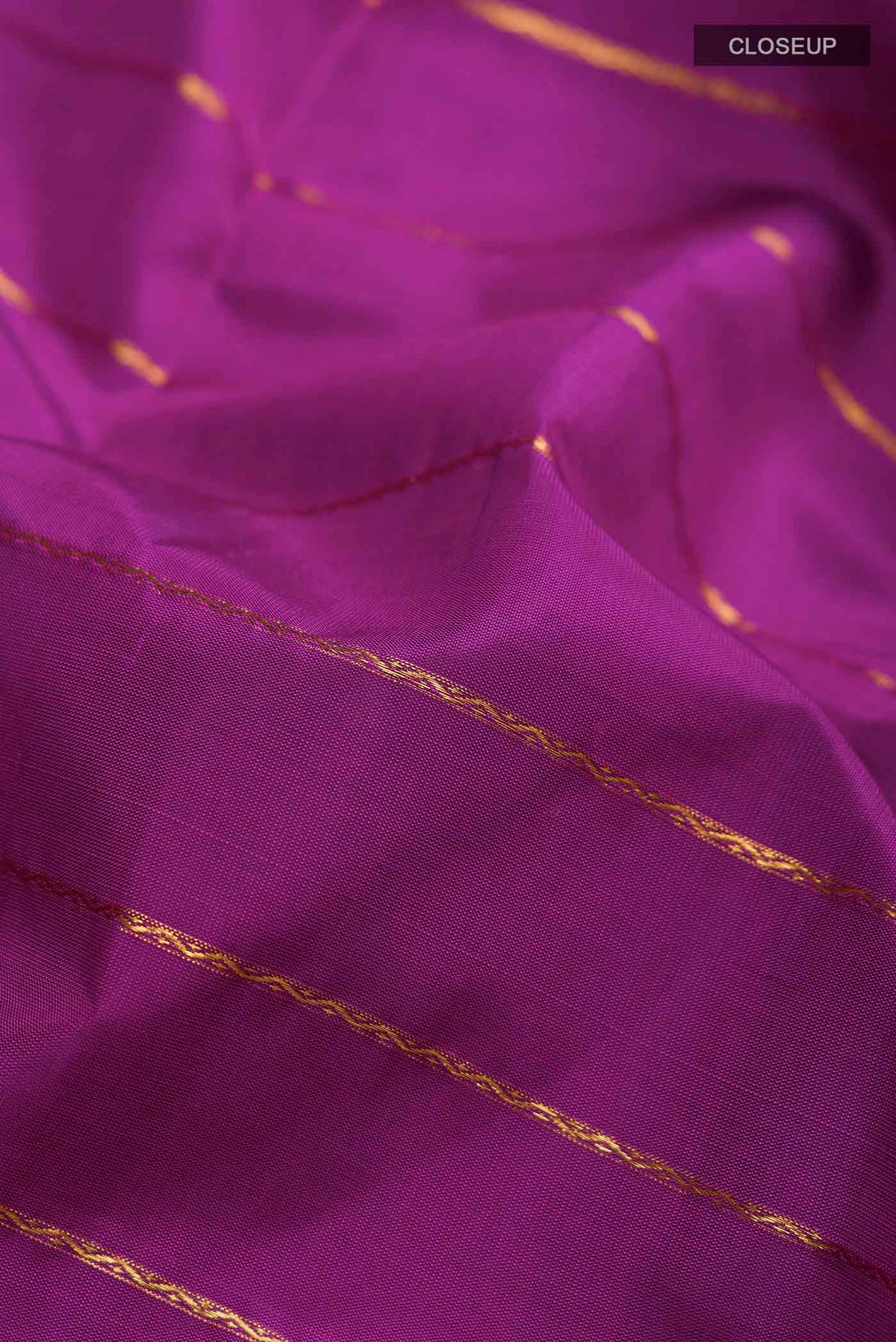 Close up of Magenta Kanchipuram Silk Saree with Veldhari on the body and Zari Border displaying folds