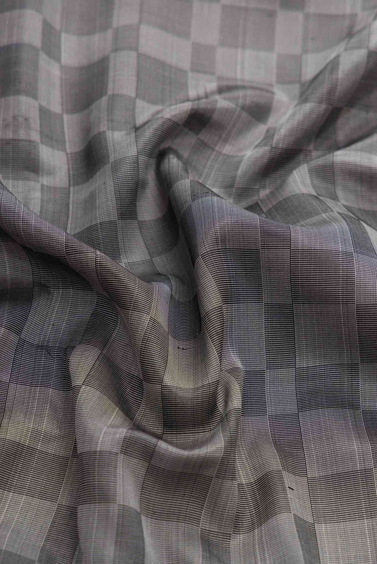 Close up of Grey Dual Tone Kanchipuram Silk Saree with Checked design on the body and Zari Border displaying folds
