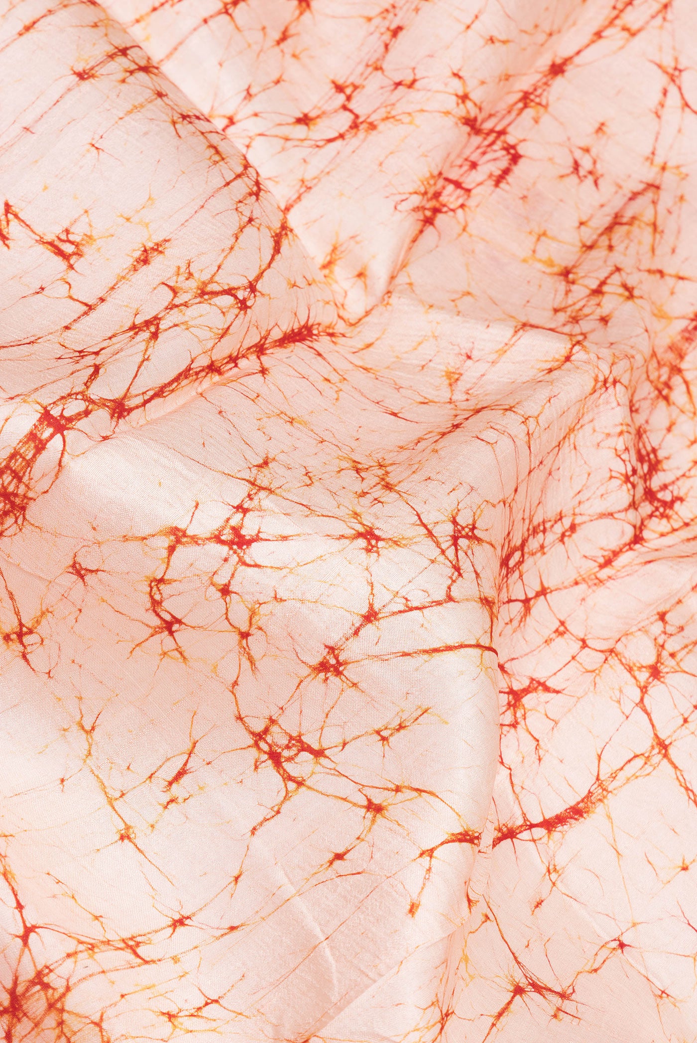 Close up of Peach Printed Silk Saree with Batik Print on the body and Printed Border.  displaying folds