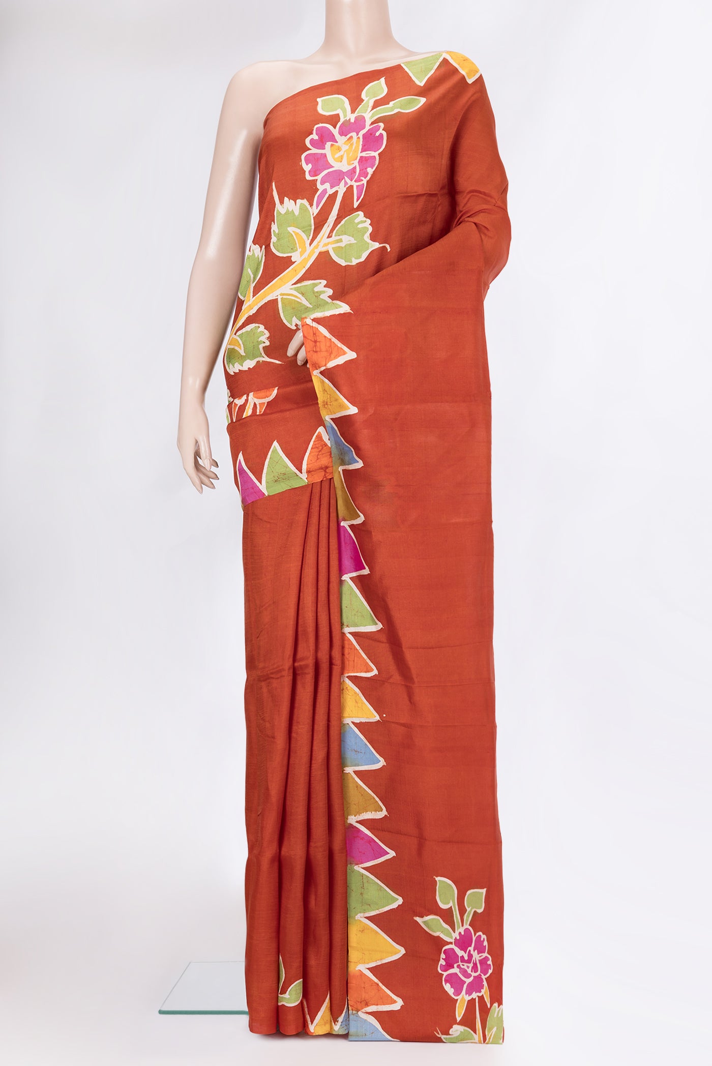 Rust Printed Silk Saree with Printed design on the body and Fancy Border.  displayed on a mannequin