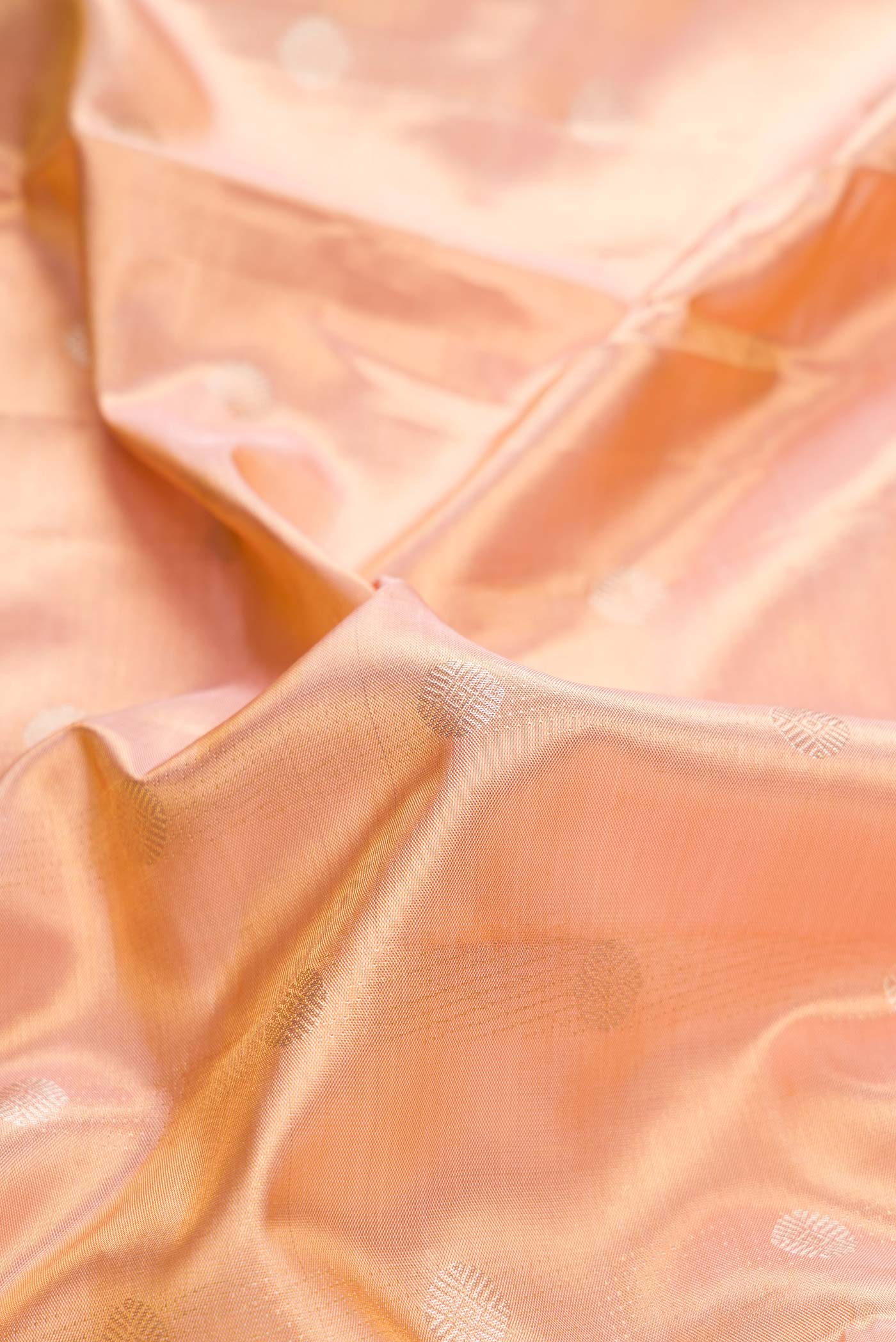 Close up of Peach Dual Tone Kanchipuram Tissue Silk Saree with Zari Brocade on the body and Zari Border displaying folds