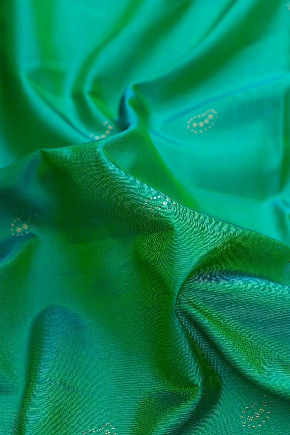 Close up of Green Dual Tone Soft Silk Saree with Zari Butta on the body and Zari Border displaying folds