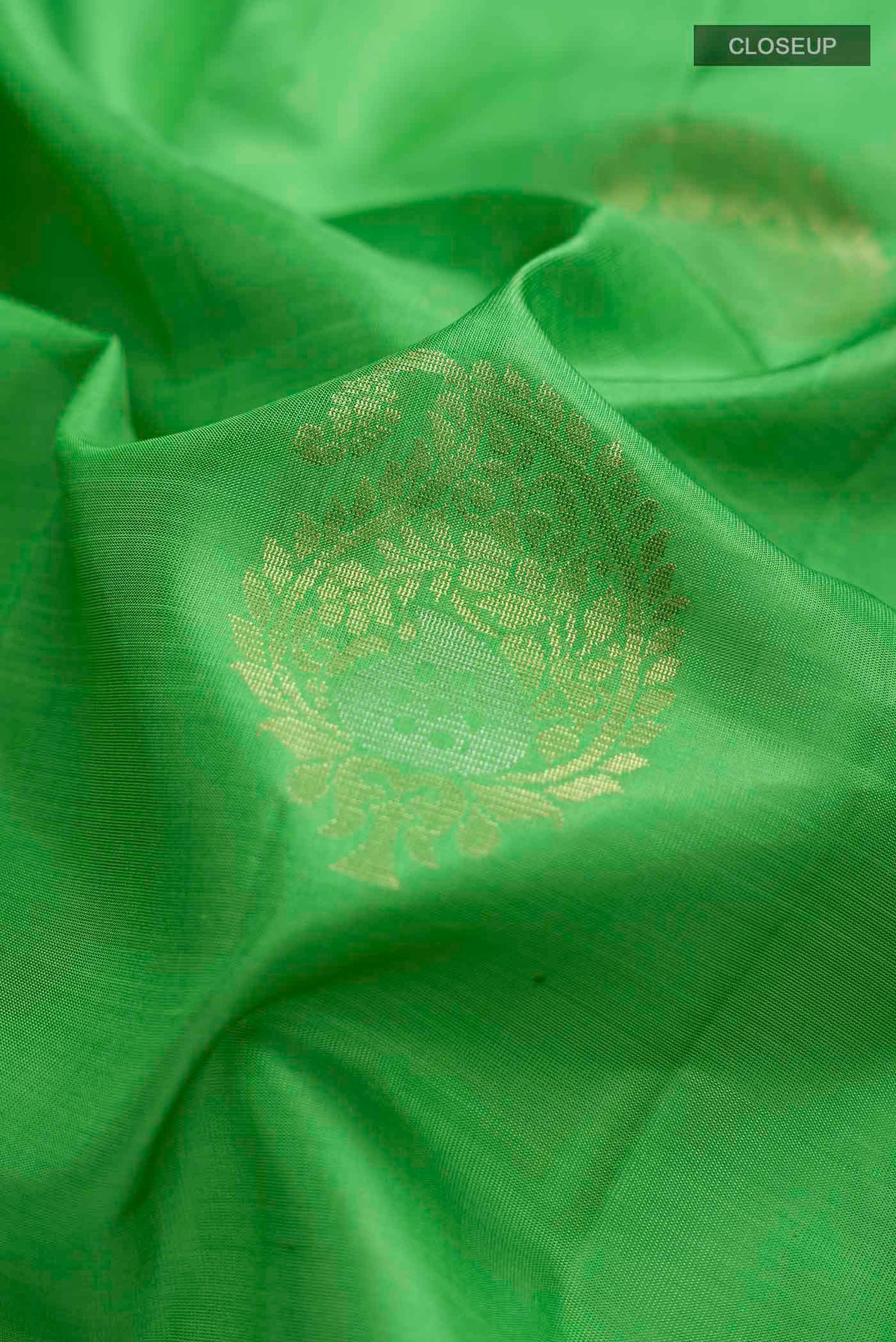 Close up of Green Soft Silk Saree with Zari Butta on the body and Zari Border displaying folds