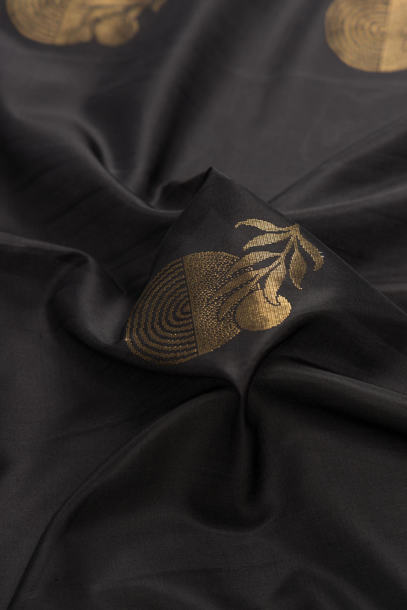 Close up of Black Dual Tone Soft Silk Saree with Zari Butta on the body and Zari Border displaying folds