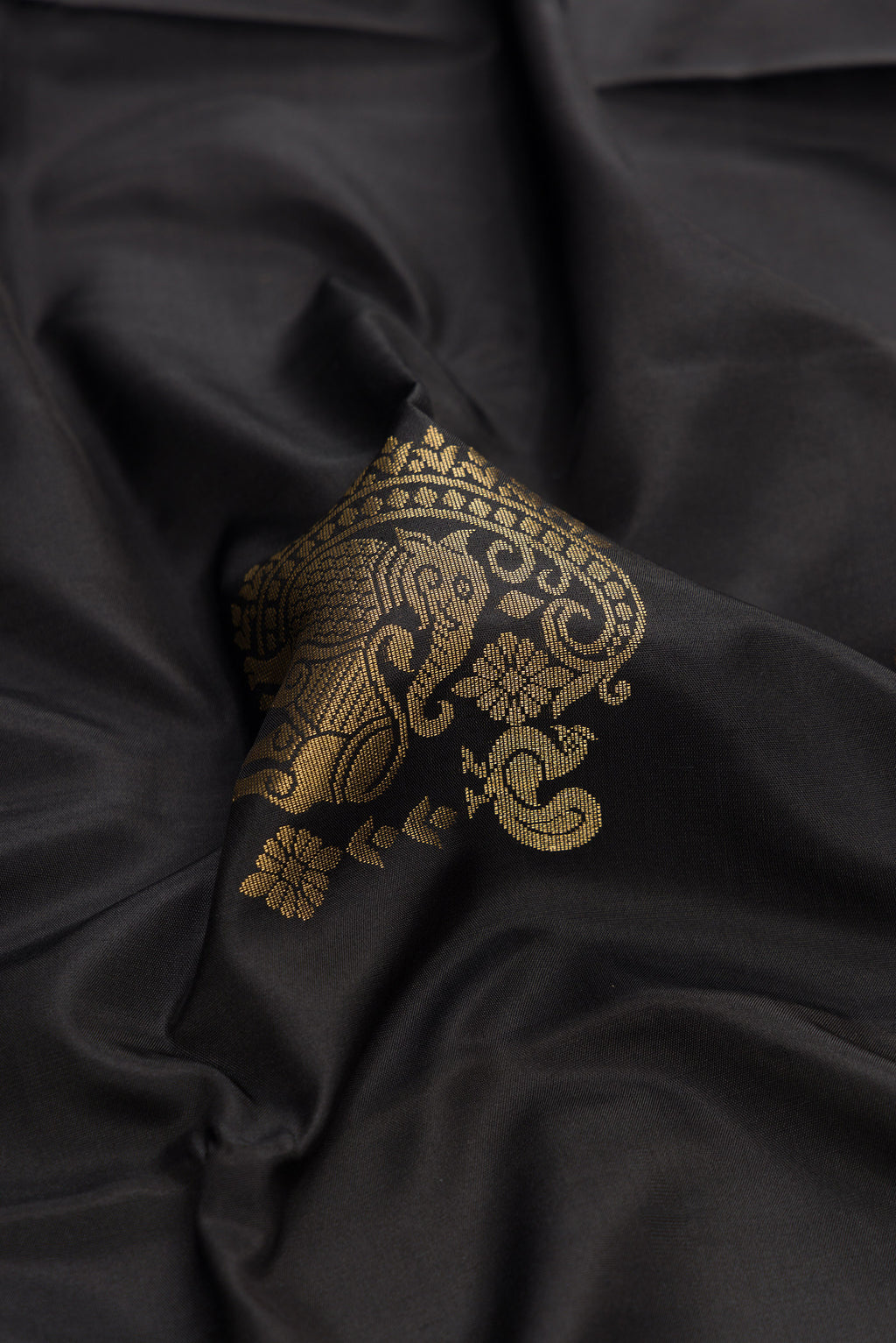Close up of Black Dual Tone Soft Silk Saree with Zari Butta on the body and Zari Border.  displaying folds