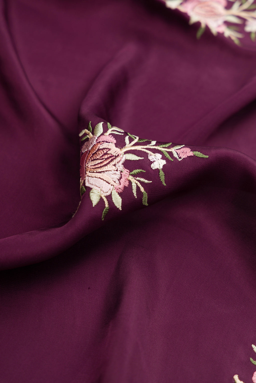 Close up of Burgundy Dual Tone Crepe Saree with Embroidery on the body and Embroidery Border.  displaying folds