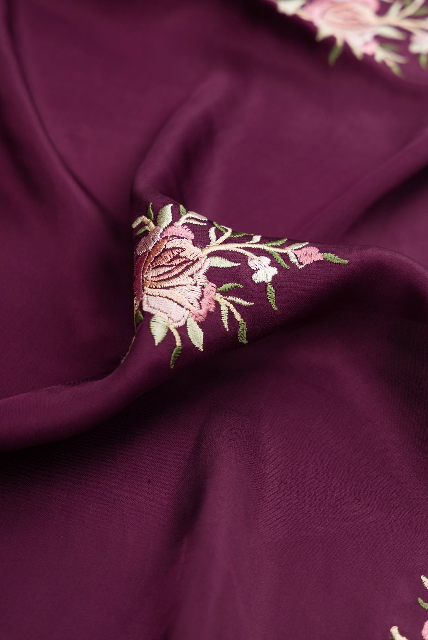 Close up of Burgundy Dual Tone Crepe Saree with Embroidery on the body and Embroidery Border.  displaying folds
