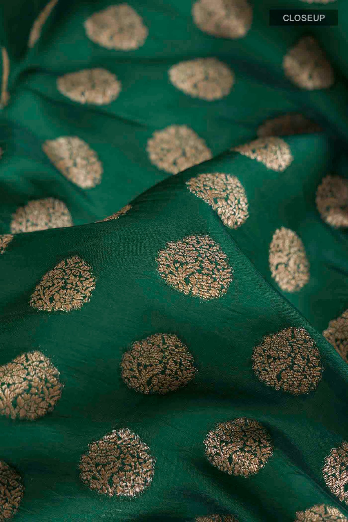 Close up of Green Banarasi Raw Silk Saree with Zari Butta on the body and Embroidery Border displaying folds