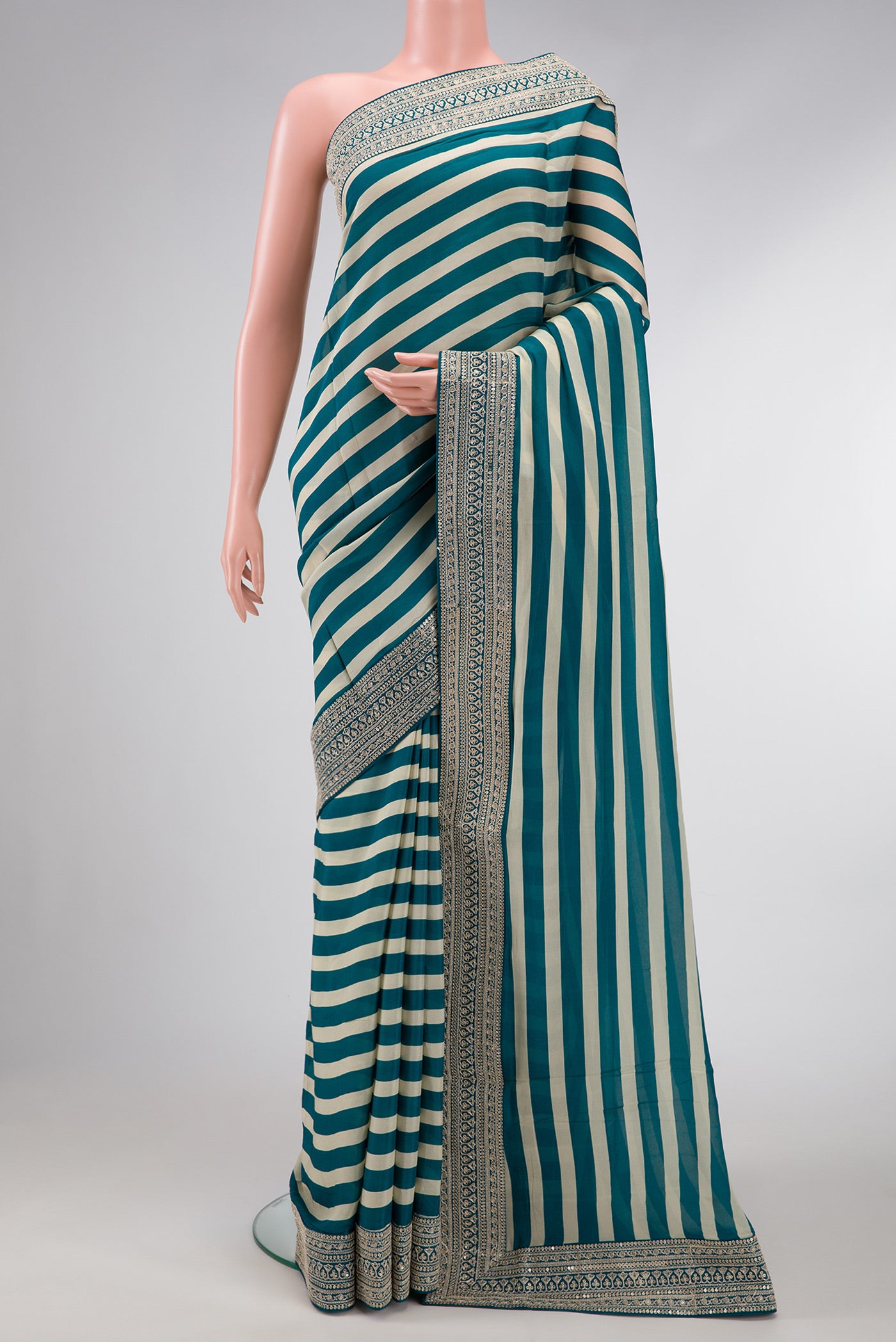 Beige and Peacock Blue Color Mysore Crepe Saree with Stripes on the body and Embroidery Border.  displayed on a mannequin