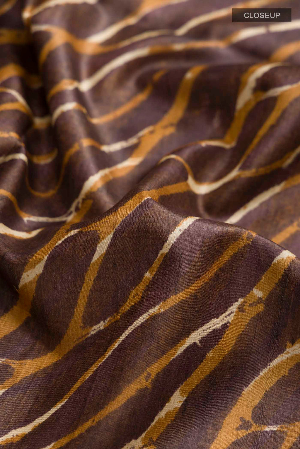 Close up of Brown Tussar Silk Saree with Printed design on the body and Zari Border displaying folds