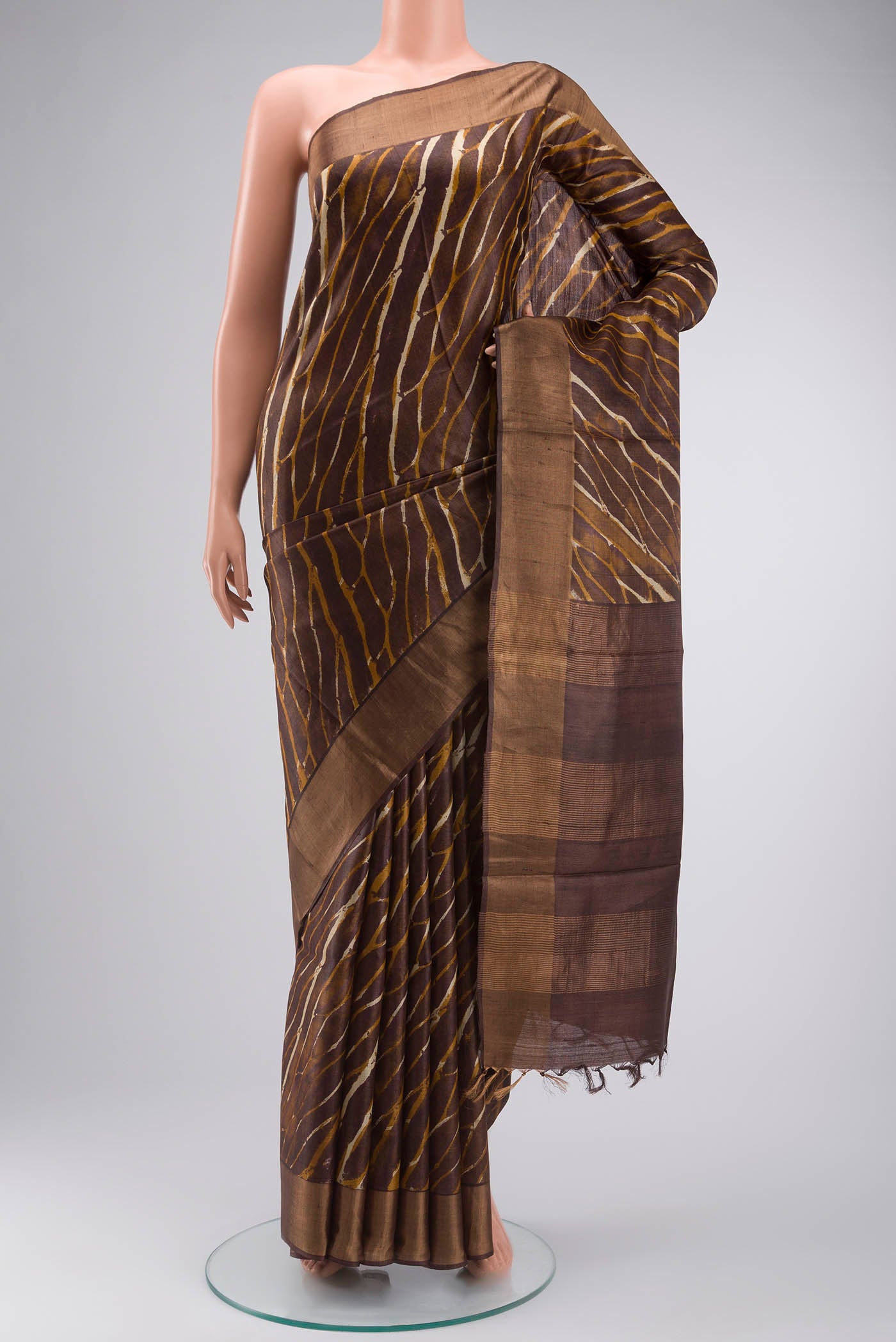 Brown Tussar Silk Saree with Printed design on the body and Zari Border displayed on a mannequin