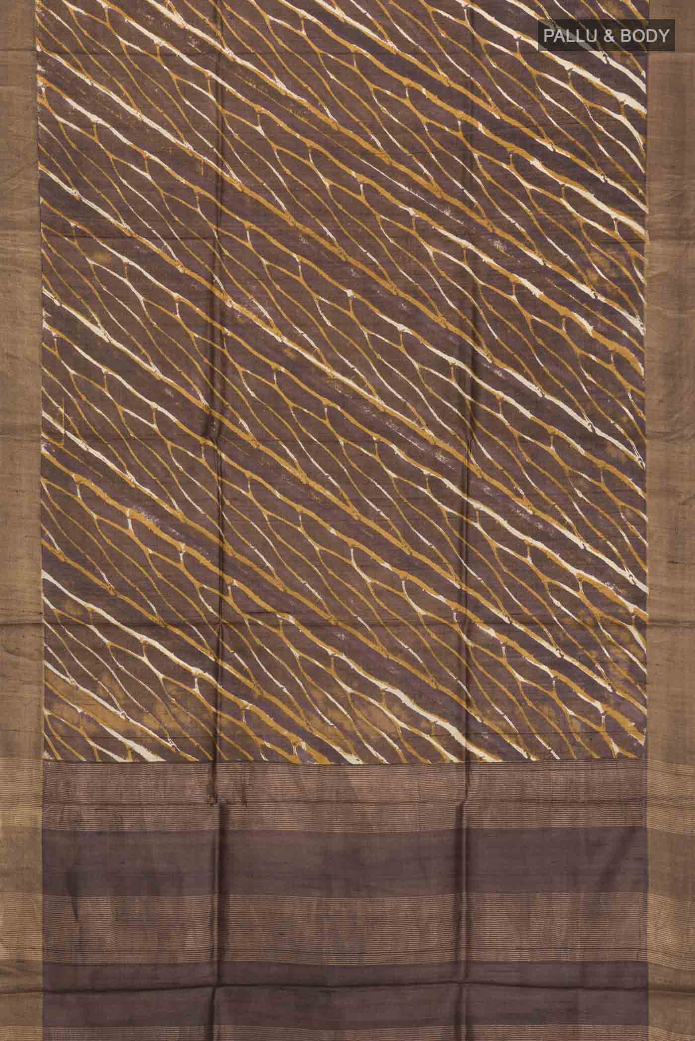 Flat view of Brown Tussar Silk Saree with Printed design on the body and Zari Border