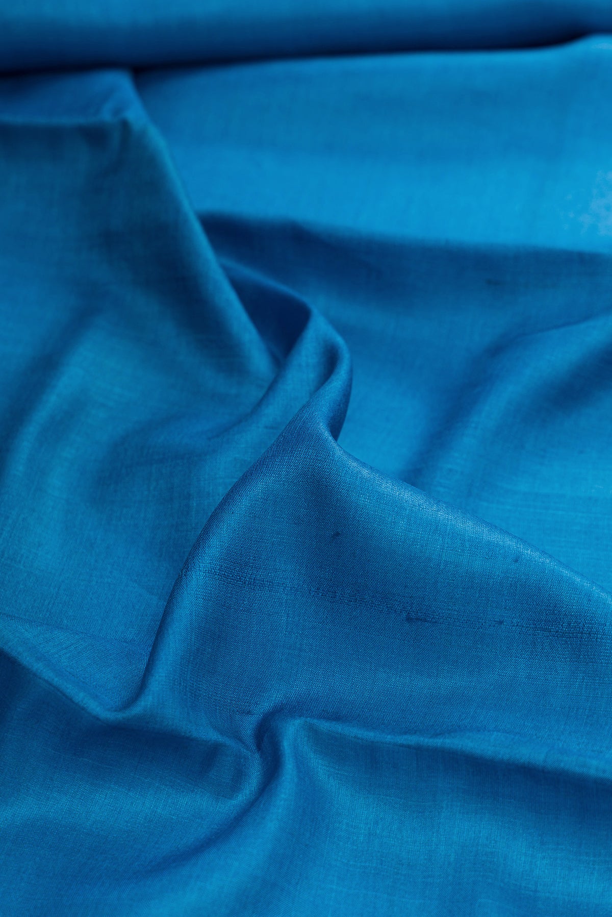 Close up of Sky Blue Dual Tone Tussar Silk Saree with Plain Body and Printed Border.  displaying folds