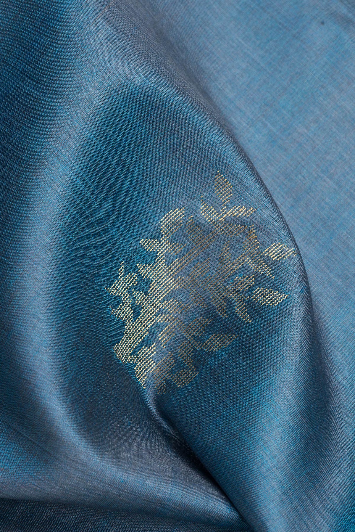 Close up of Peacock Blue Dual Tone Tussar Silk Saree with Zari And Thread Butta on the body and Zari Border.  displaying folds