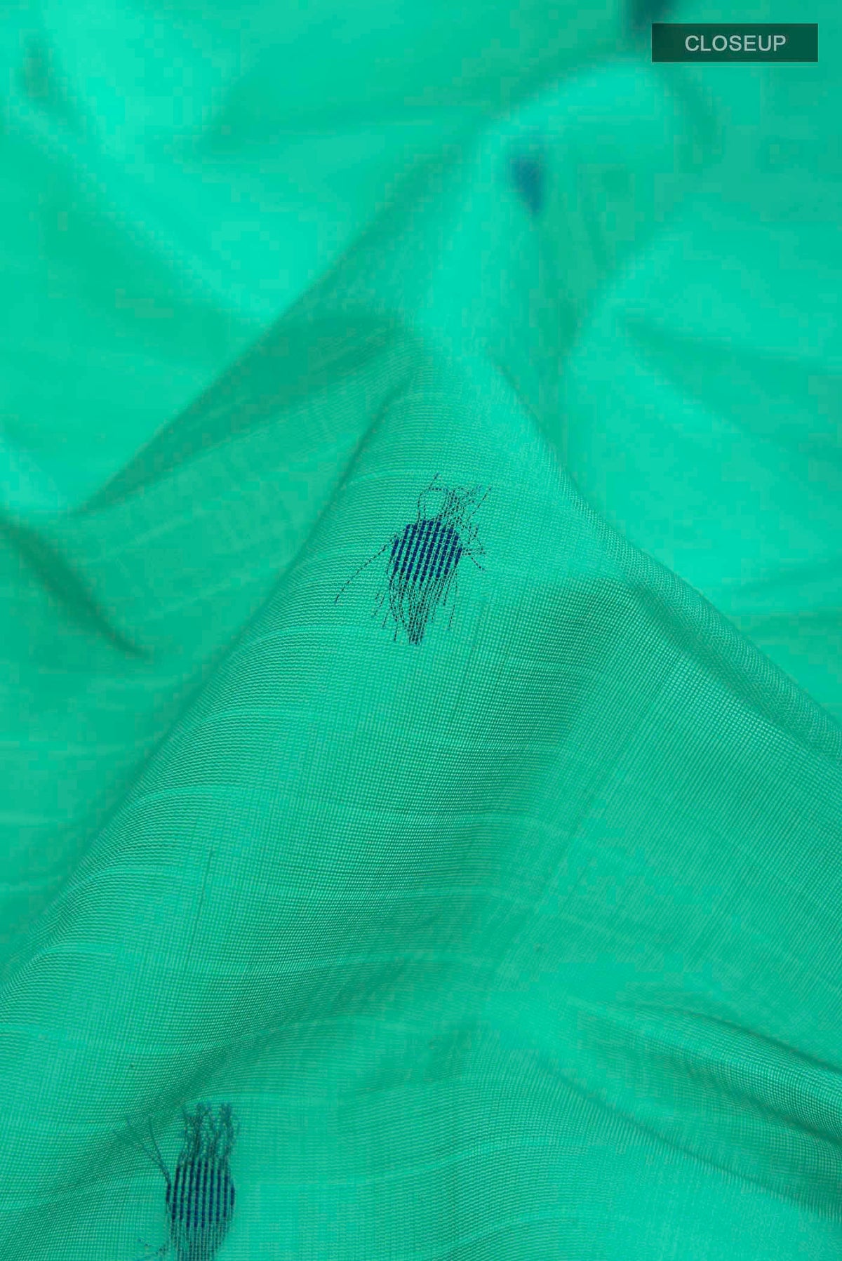 Close up of Green Silk Cotton Saree with Thread Butta on the body and Thread Border displaying folds