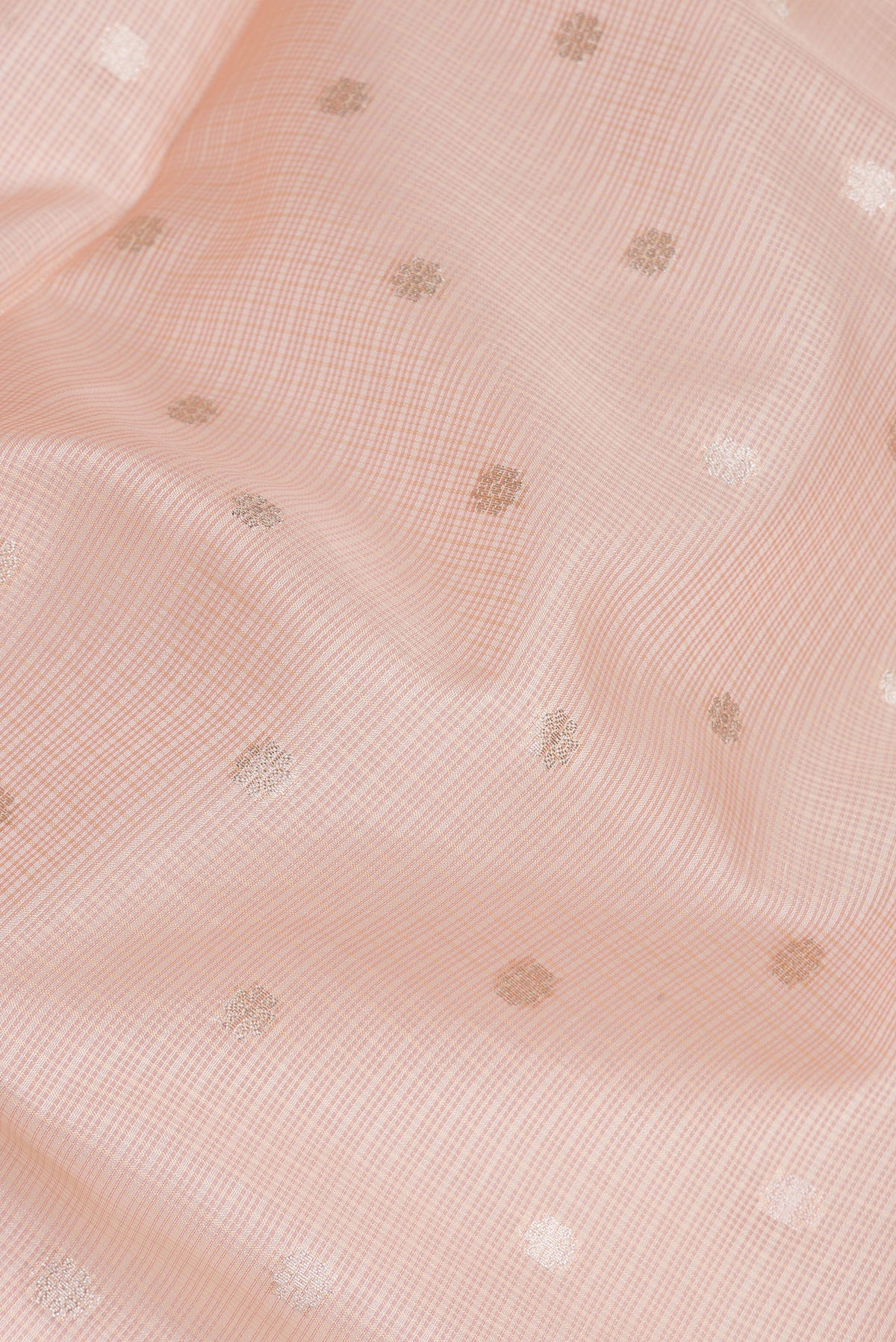 Close up of Peach Kota Silk Saree with Zari Butta on the body and Embroidery Border.  displaying folds