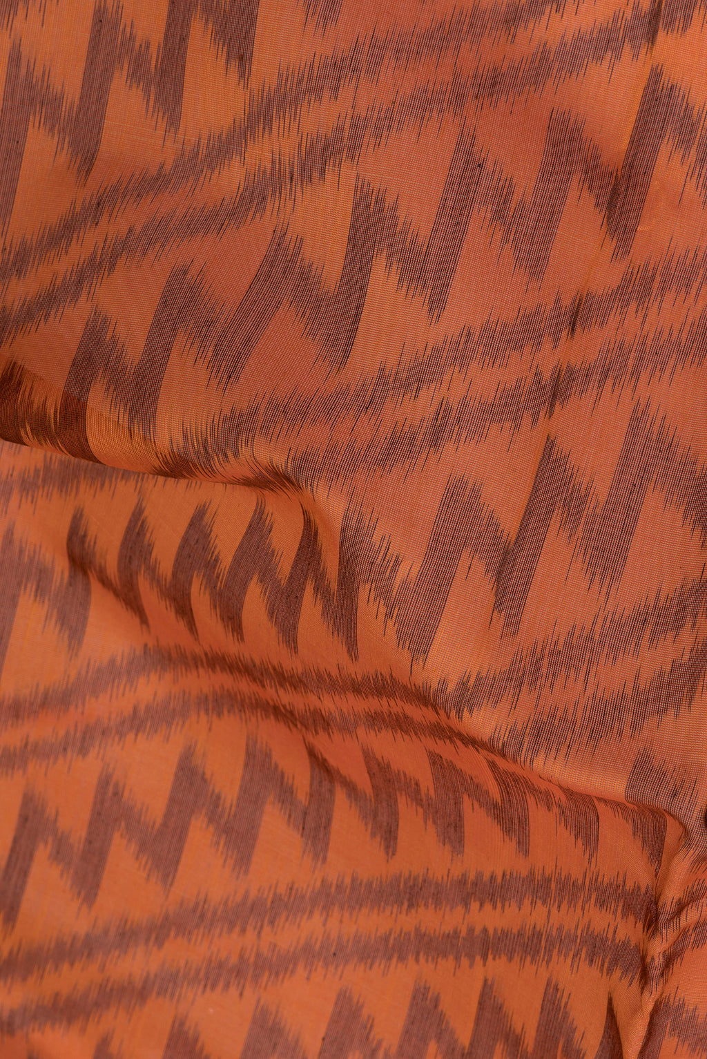 Close up of Orange Silk Cotton Saree with Ikat Print on the body and Ikat Border.  displaying folds