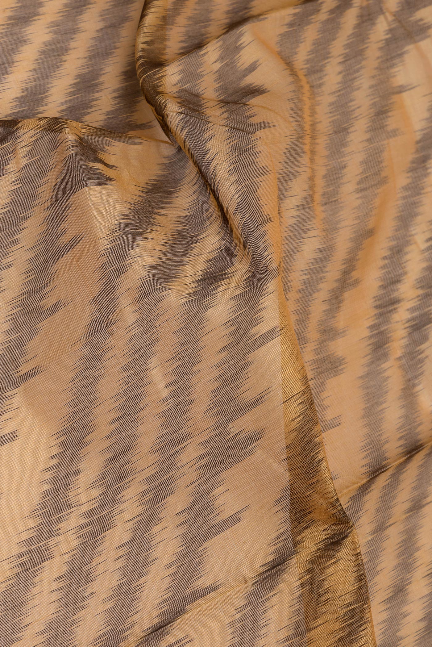 Close up of Brown Silk Cotton Saree with Ikat Print on the body and Ikat Border.  displaying folds