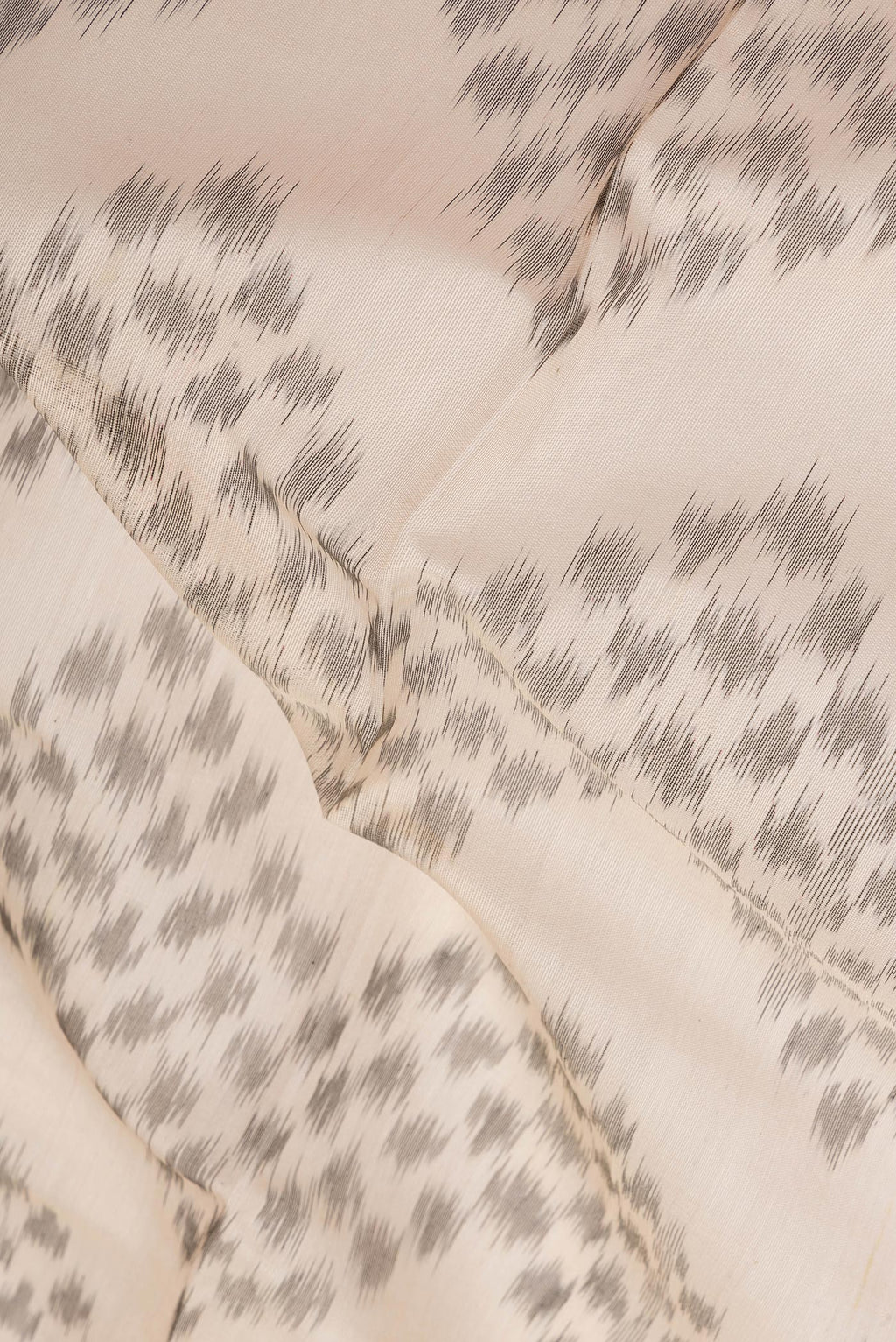 Close up of Cream Silk Cotton Saree with Ikat Print on the body and Ikat Border.  displaying folds