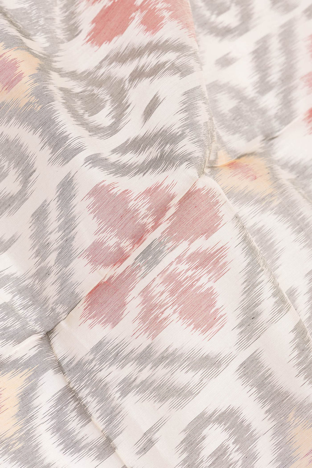 Close up of White Silk Cotton Saree with Ikat Print on the body and Zari Border.  displaying folds