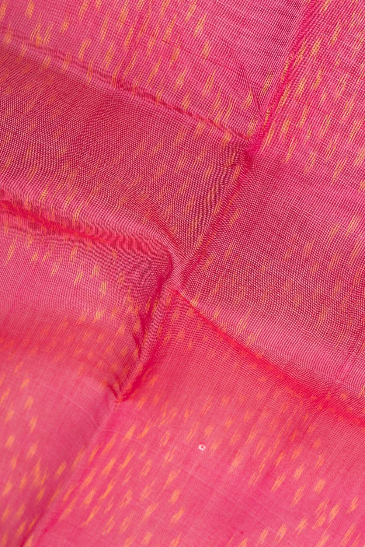 Close up of Dark Pink Silk Cotton Saree with Ikat Print on the body and Zari Border.  displaying folds