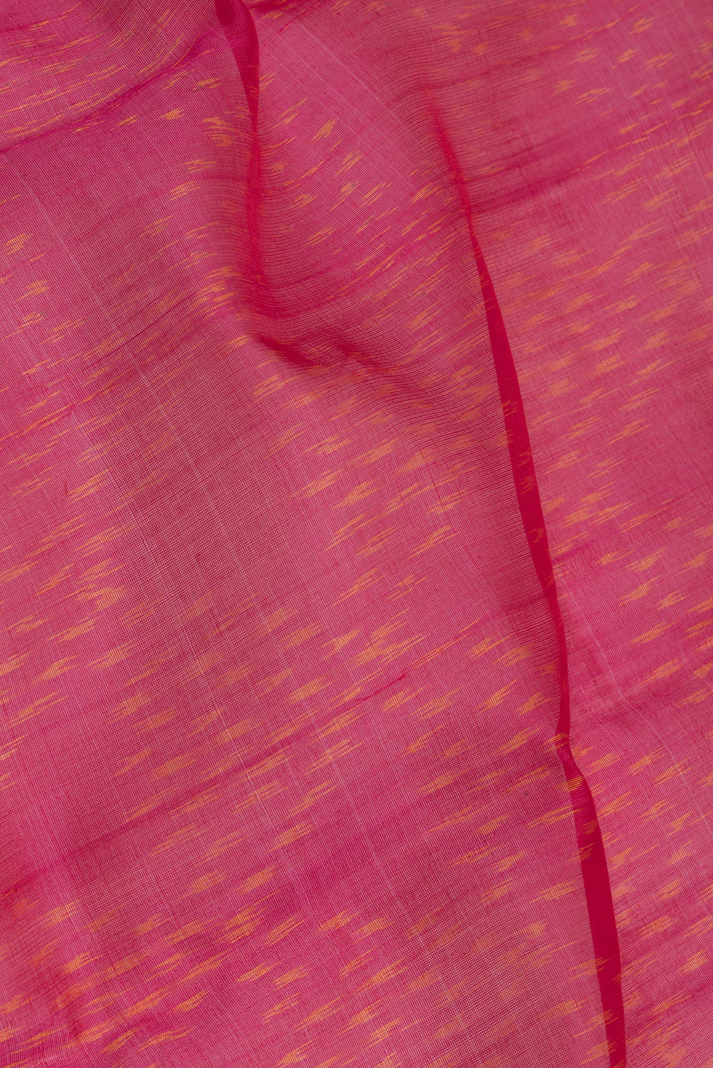 Close up of Dark Pink Silk Cotton Saree with Ikat Print on the body and Zari Border.  displaying folds
