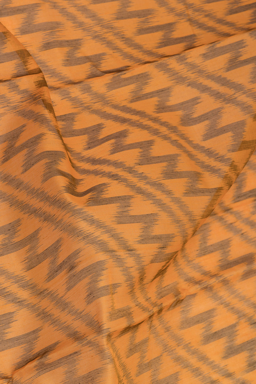 Close up of Mustard Silk Cotton Saree with Ikat Print on the body and Ikat Border.  displaying folds