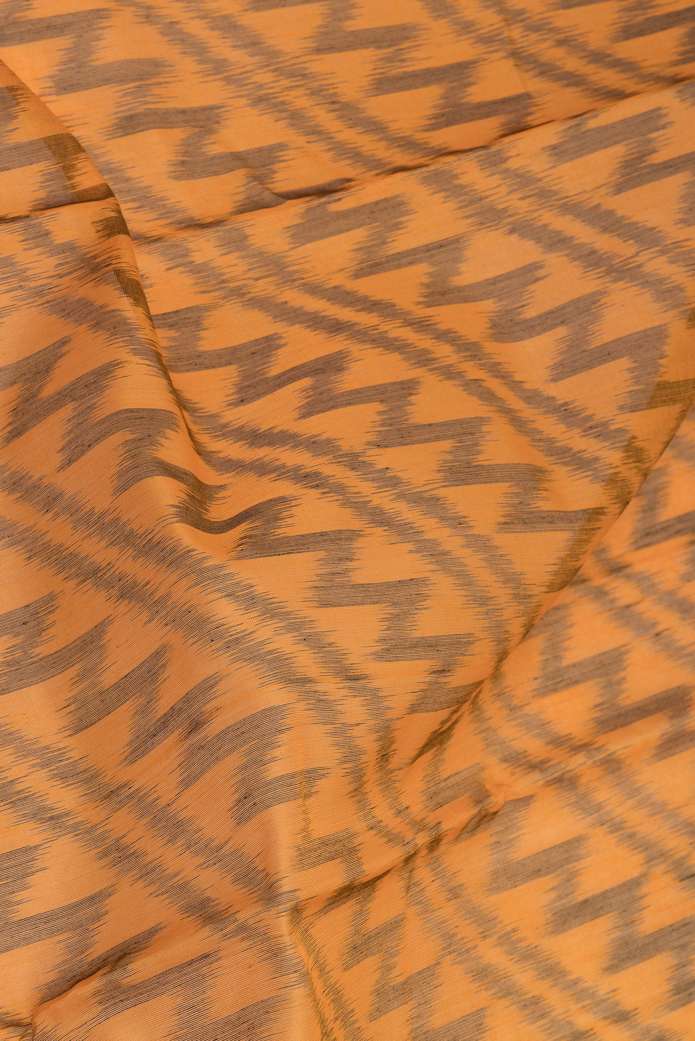 Close up of Mustard Silk Cotton Saree with Ikat Print on the body and Ikat Border.  displaying folds
