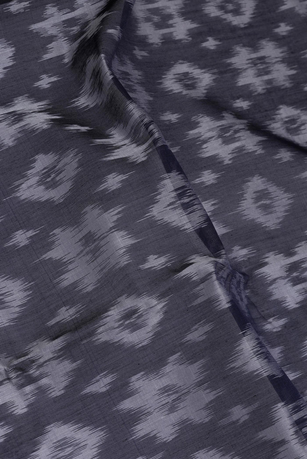 Close up of Black Silk Cotton Saree with Ikat Print on the body and Zari Border.  displaying folds