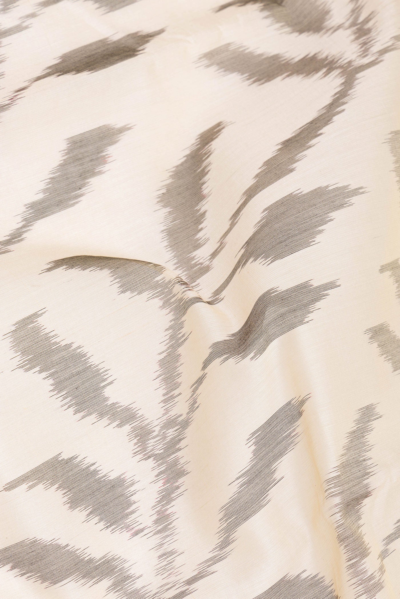 Close up of Beige Silk Cotton Saree with Ikat Print on the body and Zari Border.  displaying folds