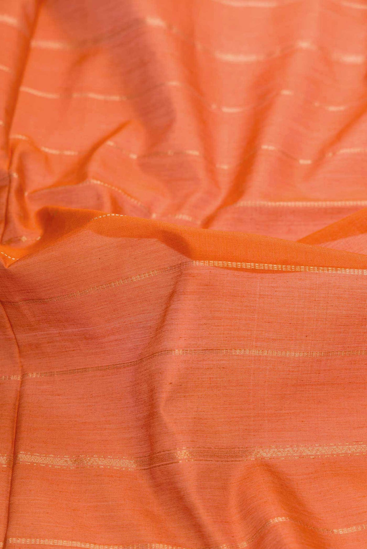 Close up of Orange Dual Tone Silk Cotton Saree with Stripes on the body and Zari Border displaying folds