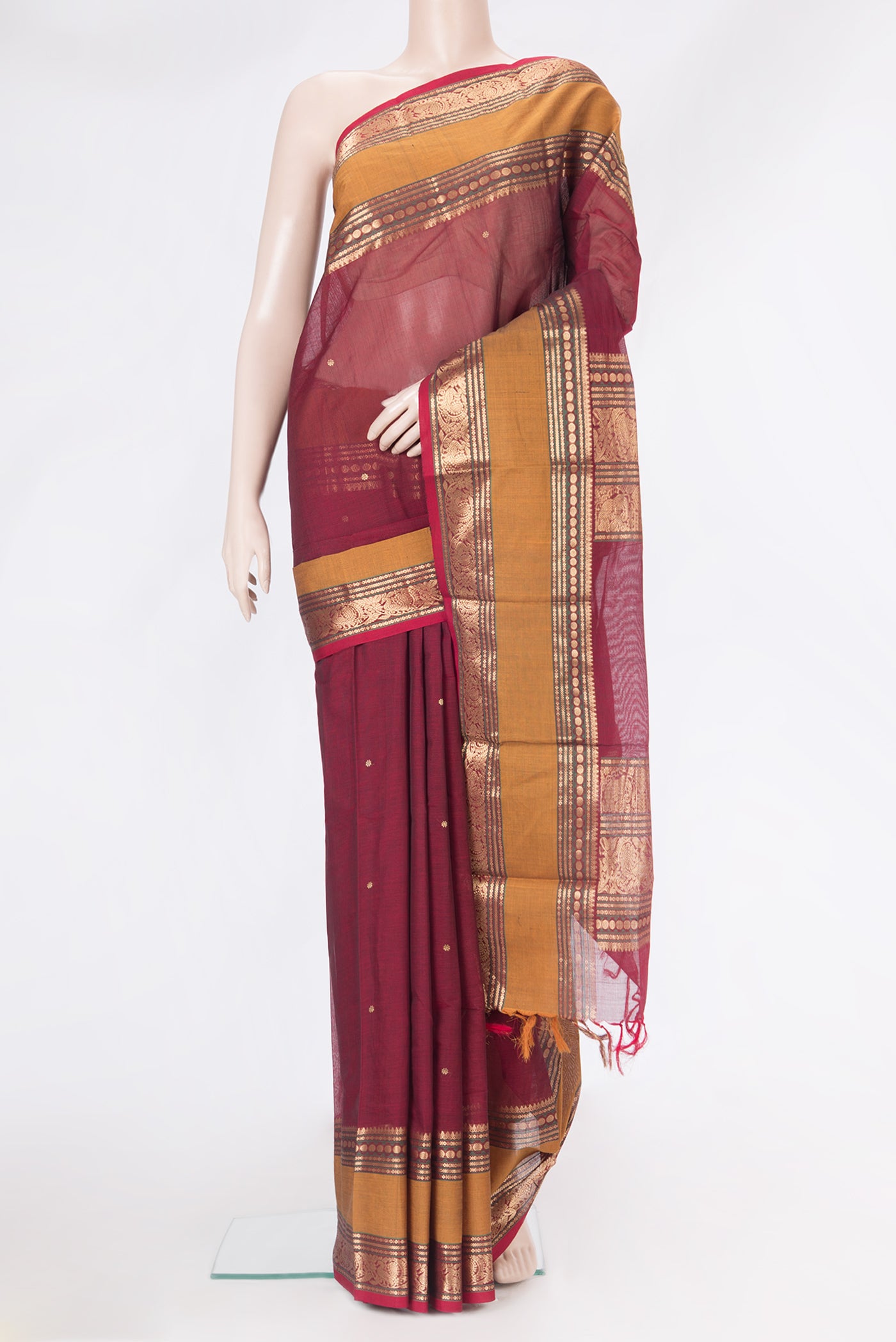 Maroon Kanchi Cotton Saree with Zari Butta on the body and Zari Border.  displayed on a mannequin