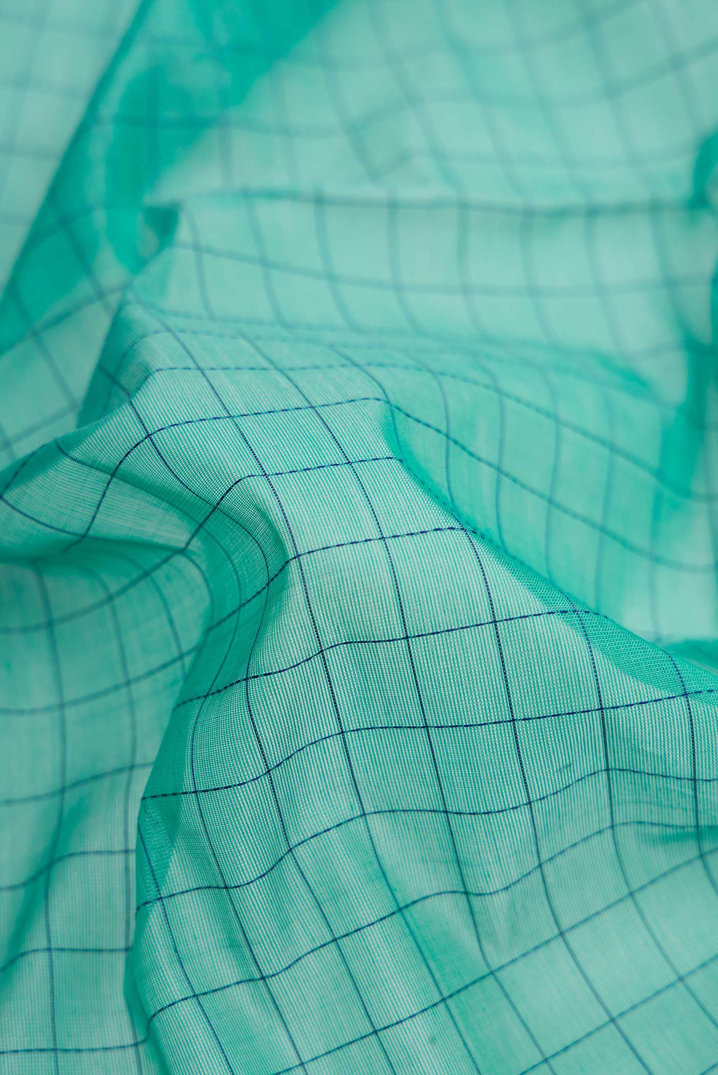 Close up of Sea Green Dual Tone Silk Cotton Saree with Checked design on the body and Fancy Border.  displaying folds