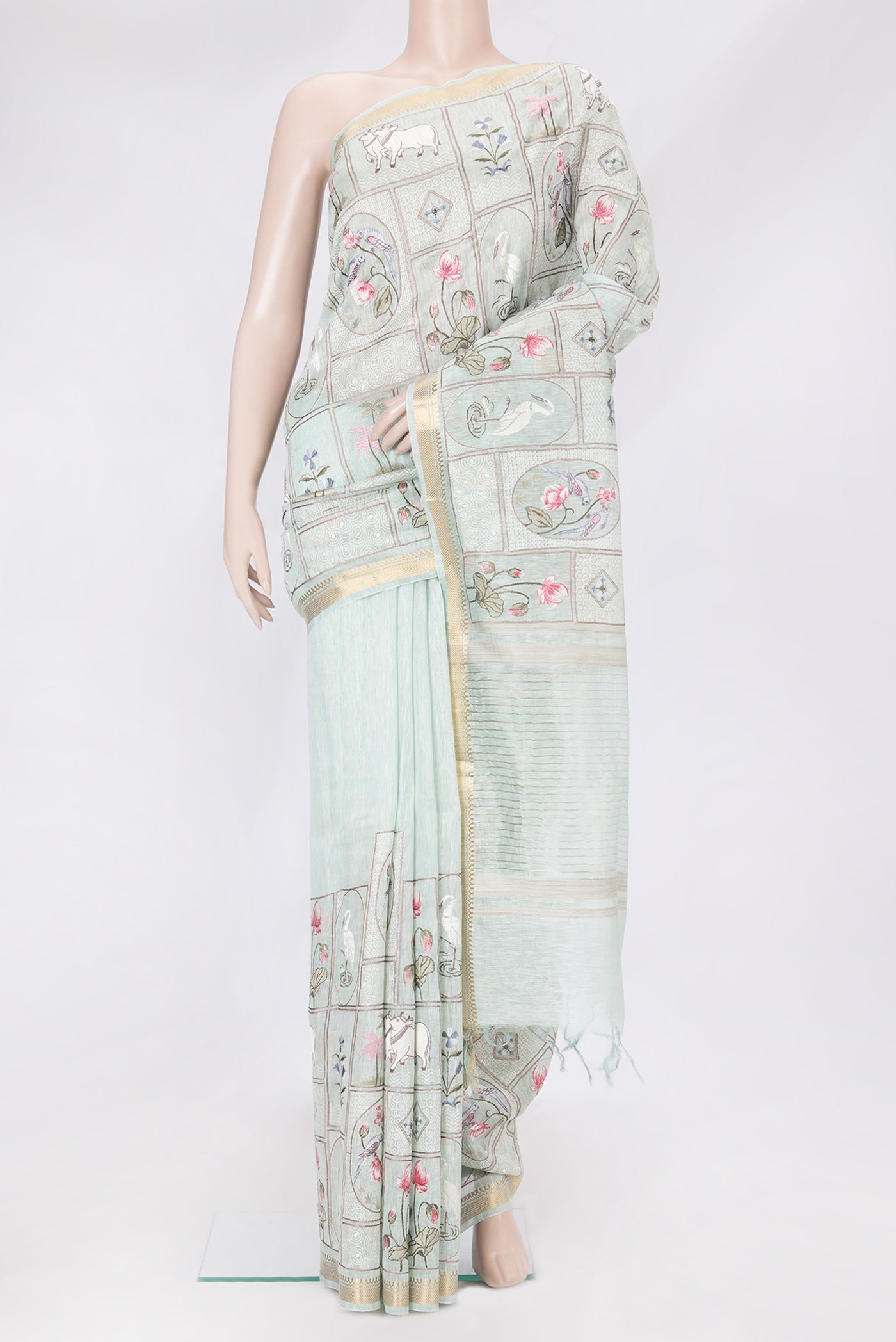 Mint Green Linen Saree with Embroidery on the body and Zari Border.  displayed on a mannequin