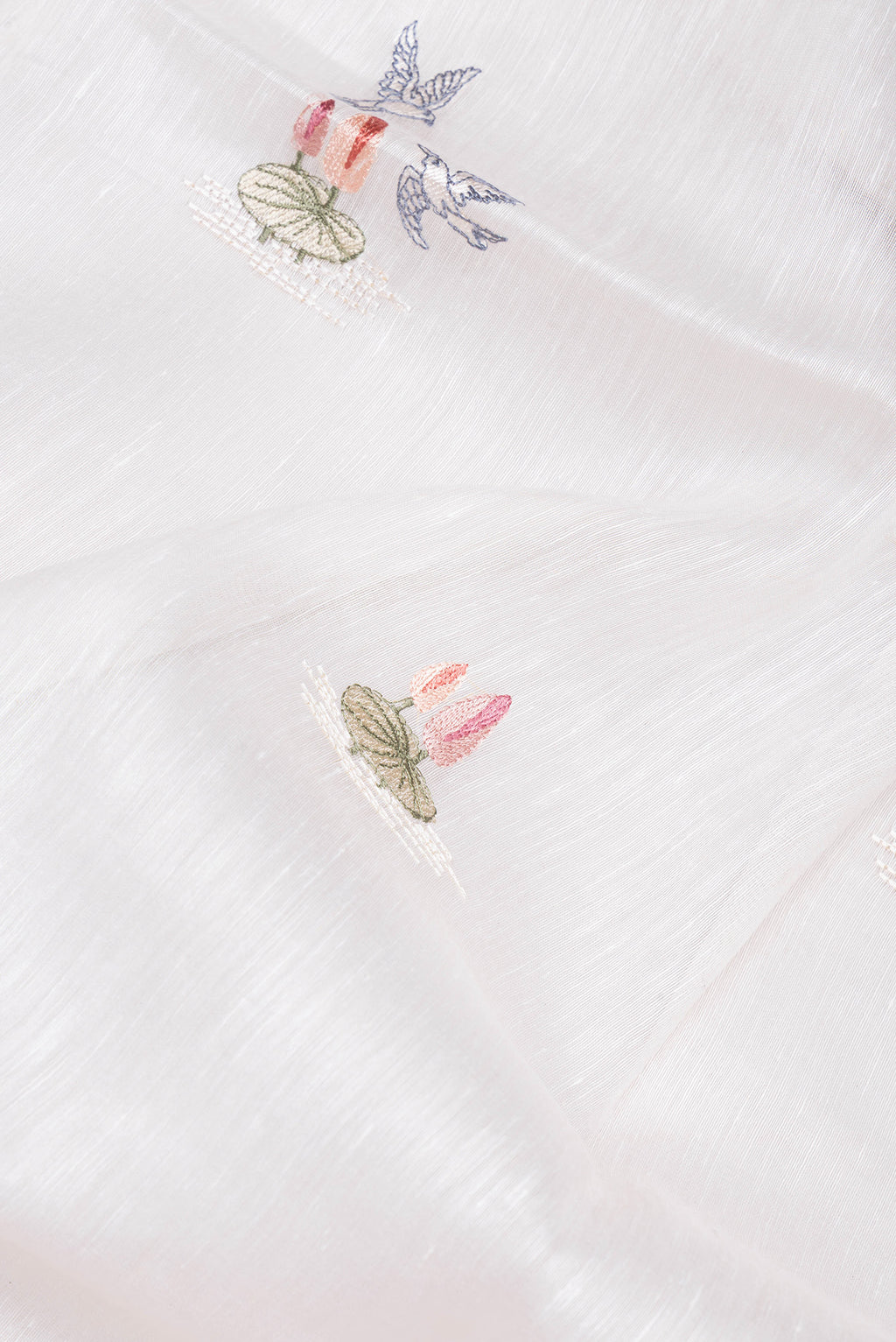 Close up of Off White Linen Saree with Embroidery on the body and Zari Border.  displaying folds