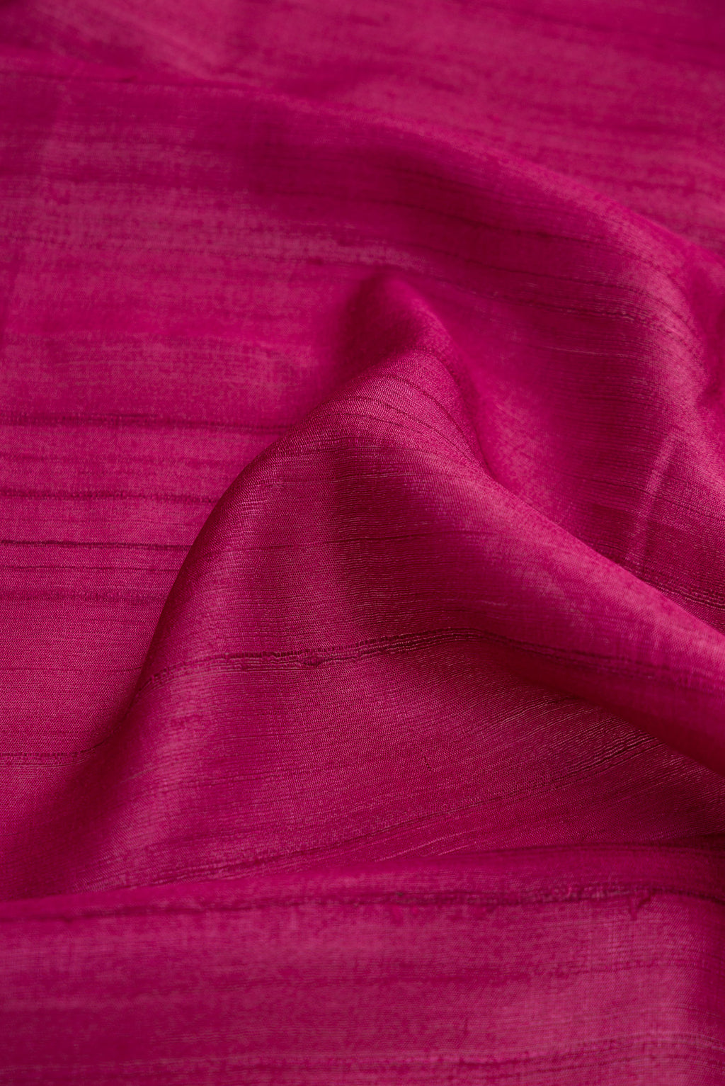 Close up of Magenta Dual Tone Tussar Silk Saree with Plain Body and Fancy Border.  displaying folds