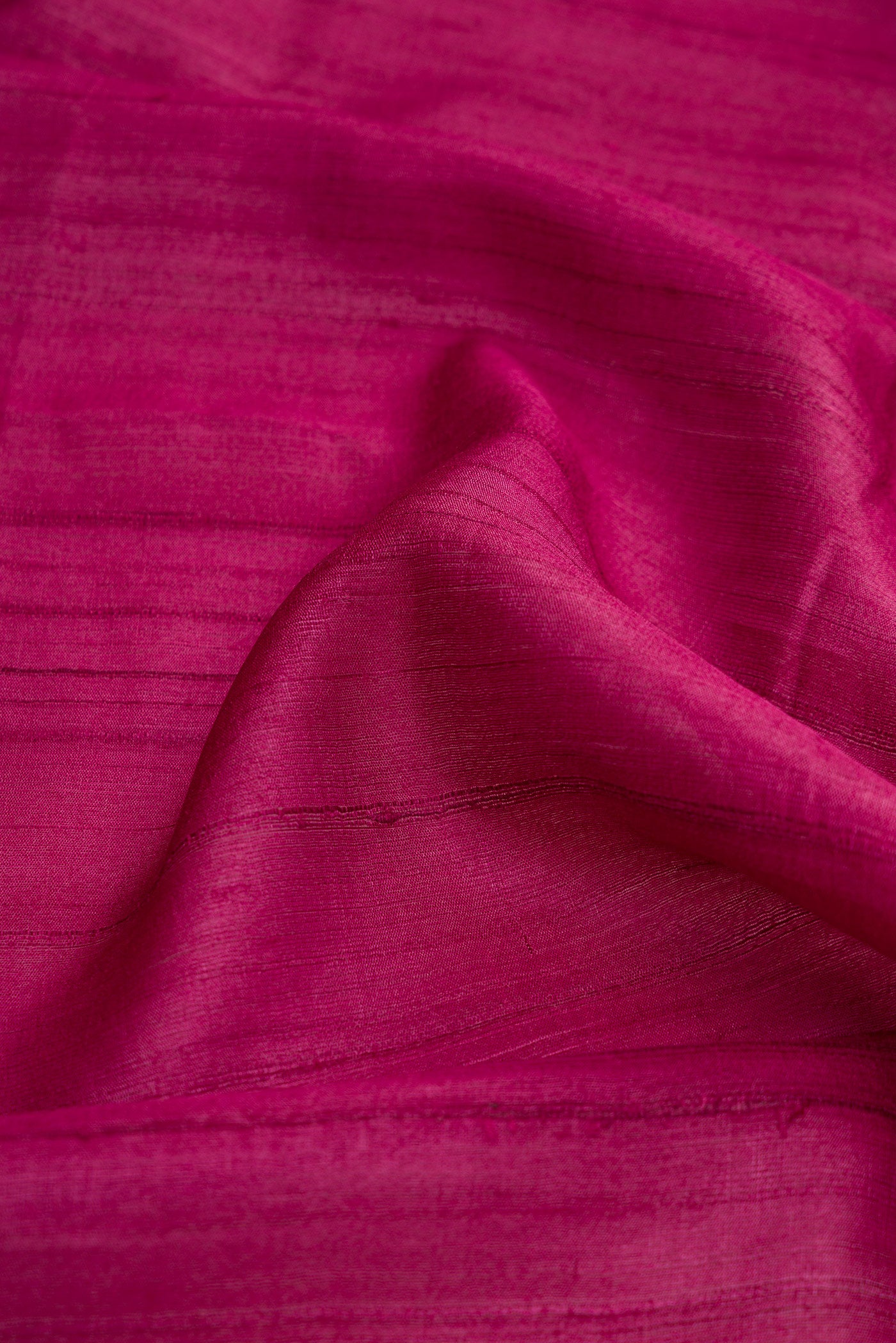 Close up of Magenta Dual Tone Tussar Silk Saree with Plain Body and Fancy Border.  displaying folds