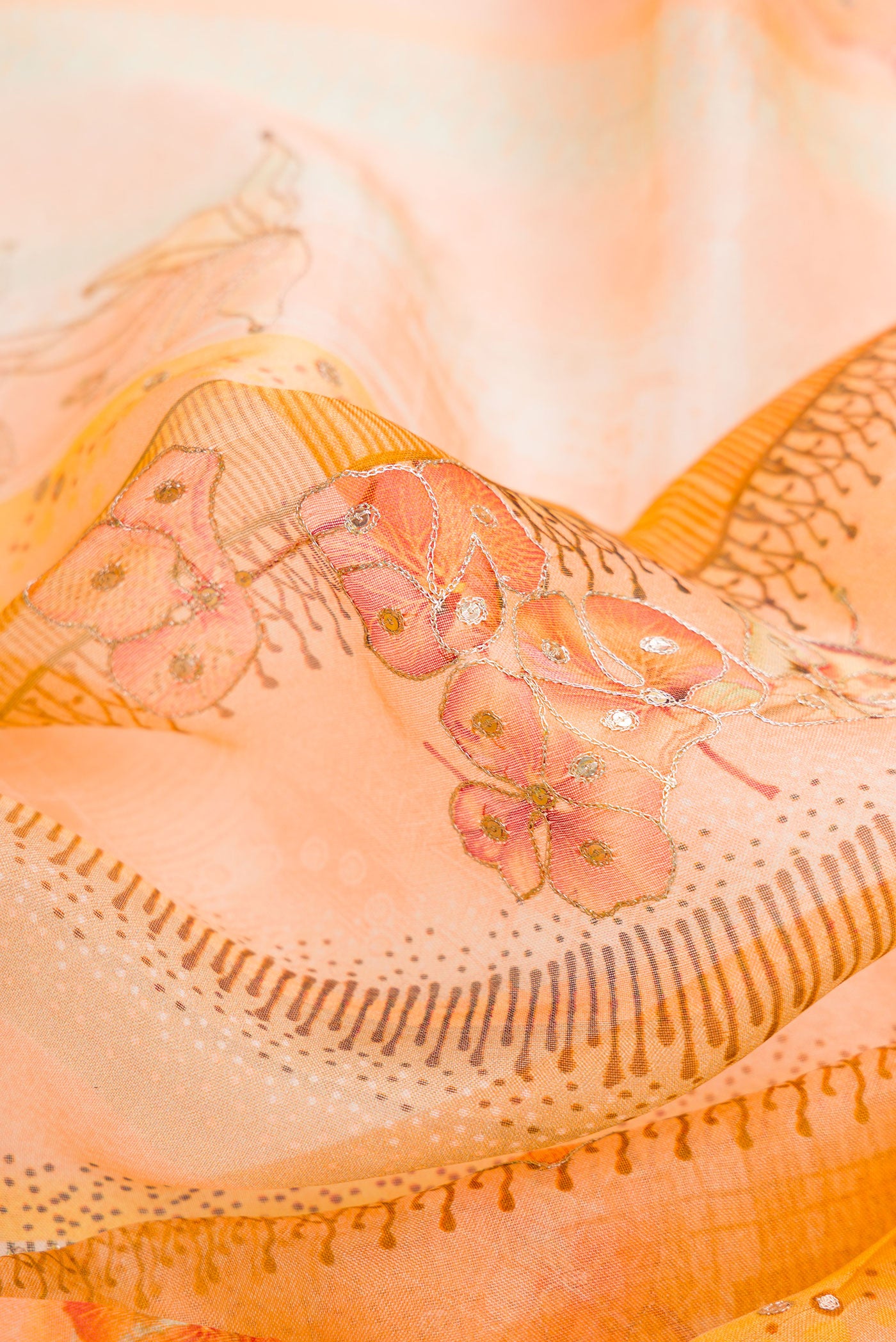 Close up of Peach Dual Tone Organza Silk Saree with Embroidery on the body and Embroidery Border.  displaying folds